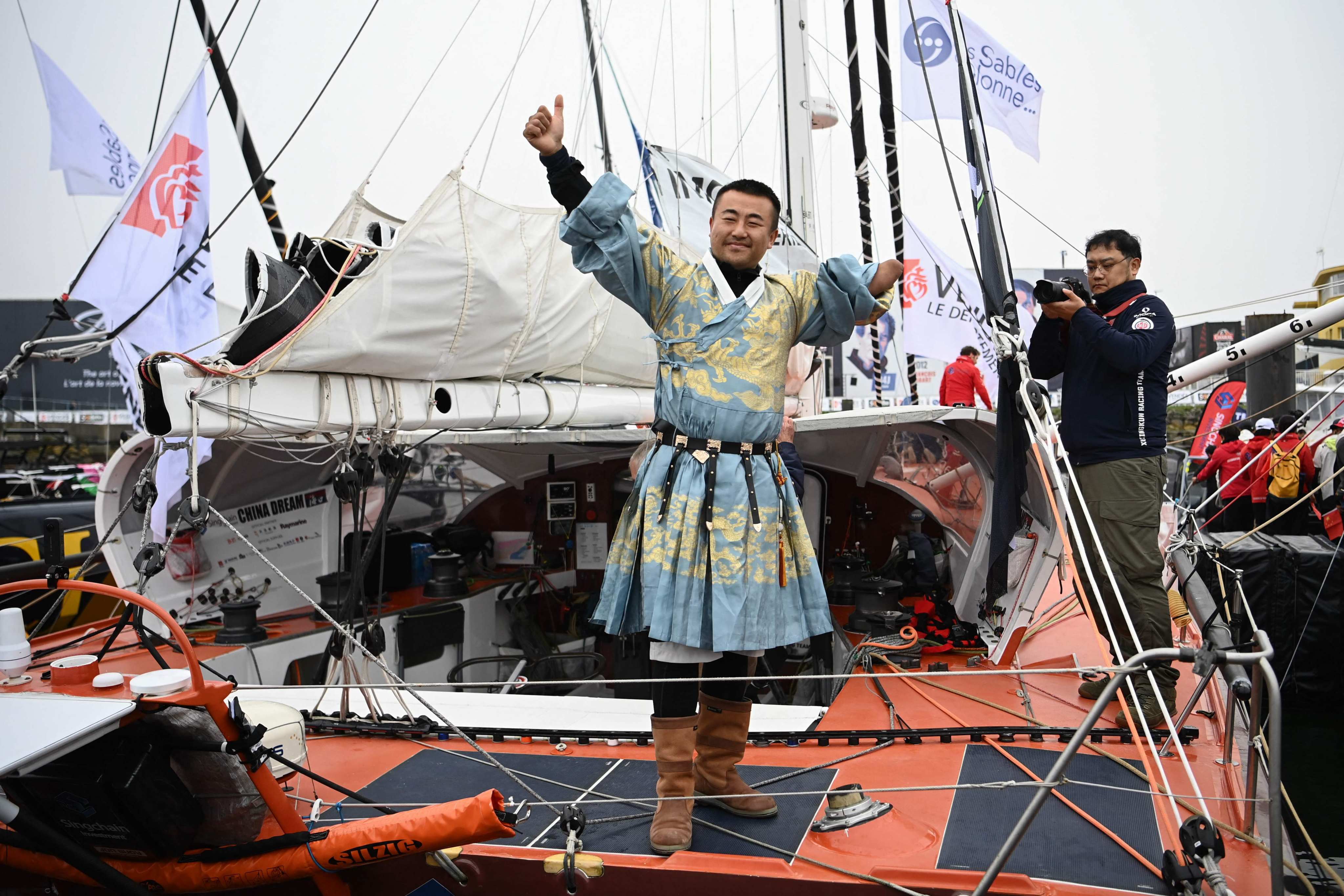 Chinese skipper Jingkun Xu waves from aboard his Imoca monohull ‘Singchaim Team Hikou’ before the start of the 10th edition of the Vendee Globe. Photo: AFP