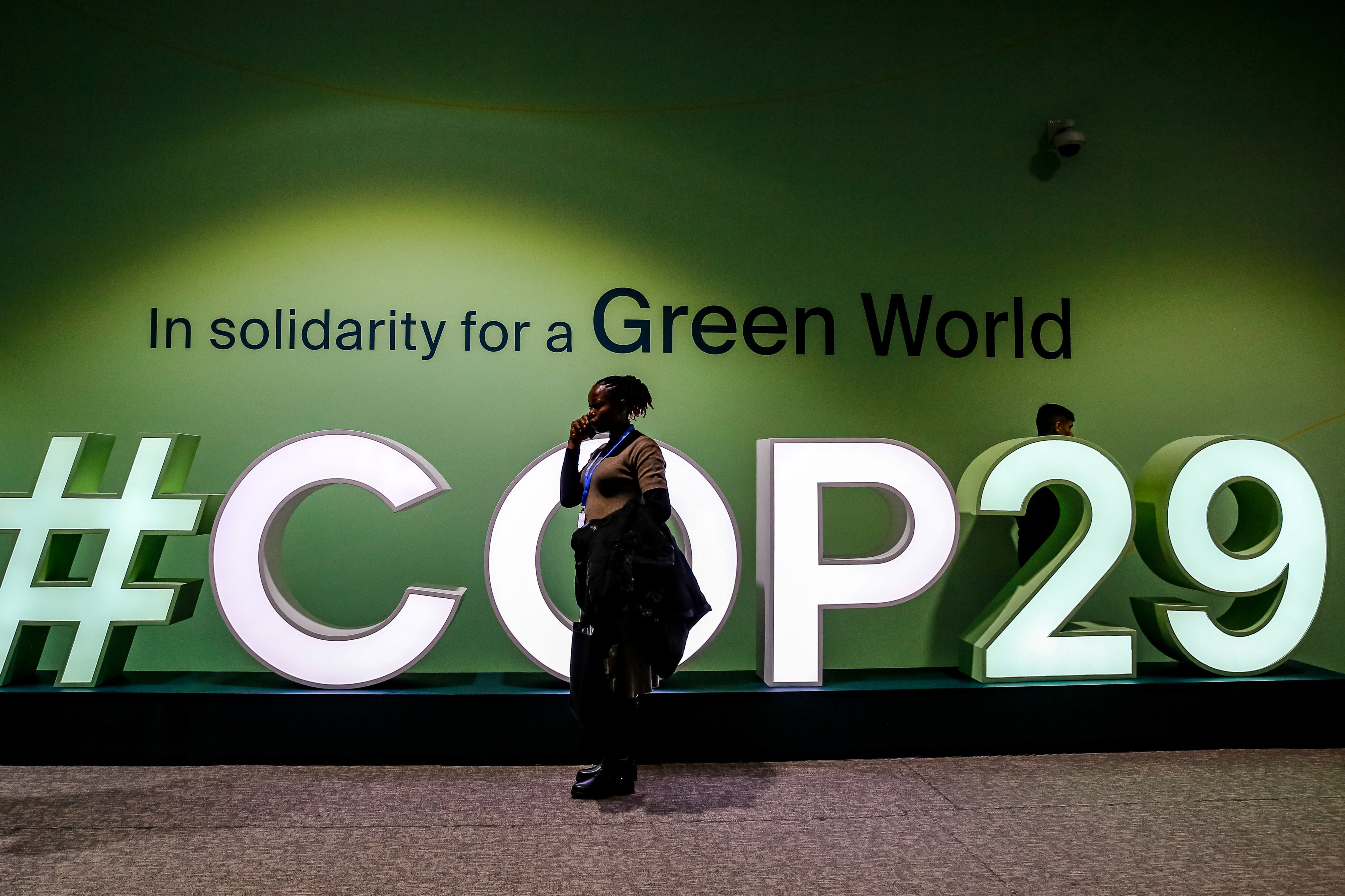 A woman walks past a logo of Cop29 in Baku Olympic Stadium, Azerbaijan. Photo: DPA