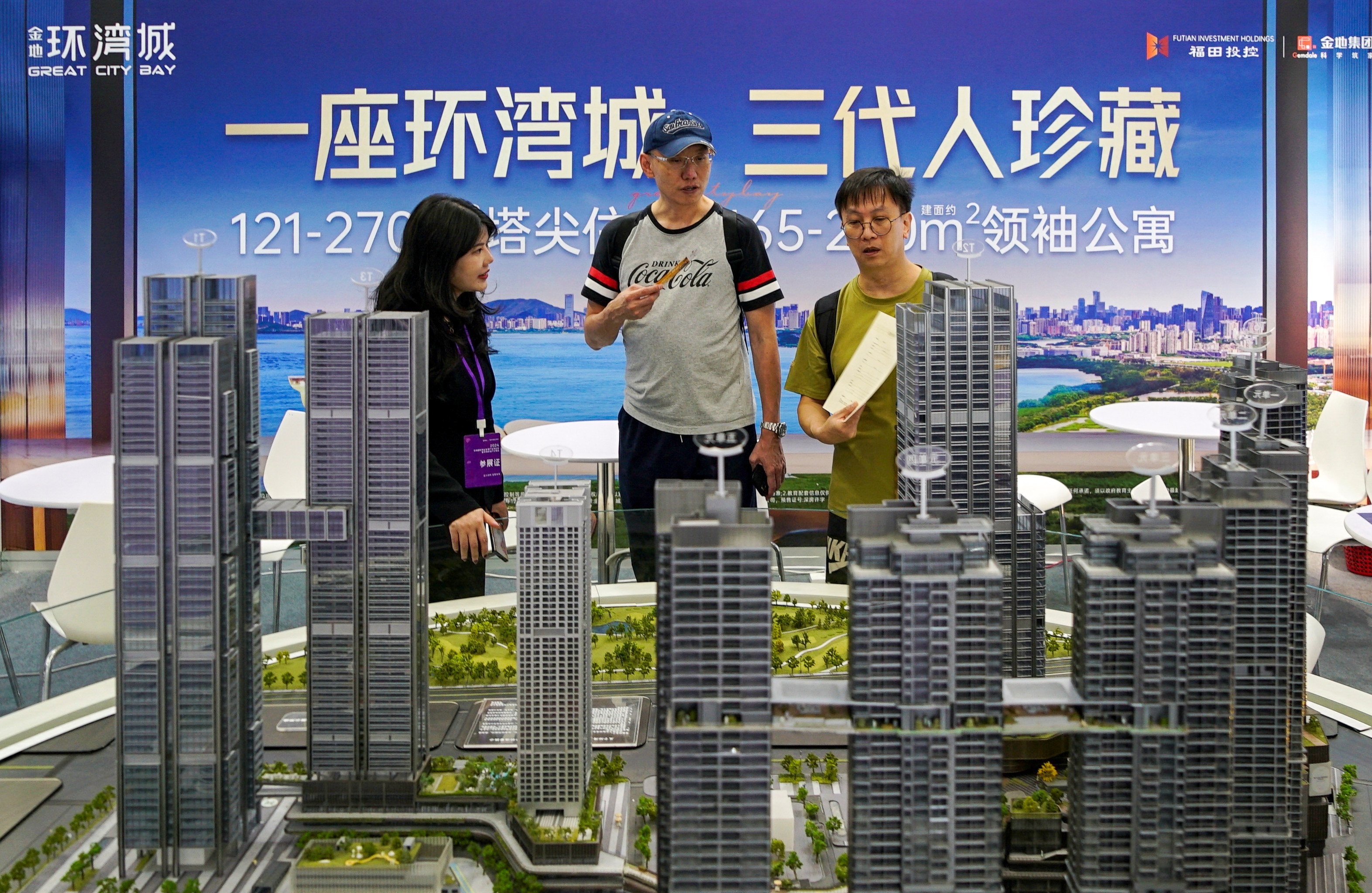 An agent speaks with potential buyers near a scale model of residential buildings at a property fair in Shenzhen, Guangdong province, on October 12, 2024. Photo: Reuters