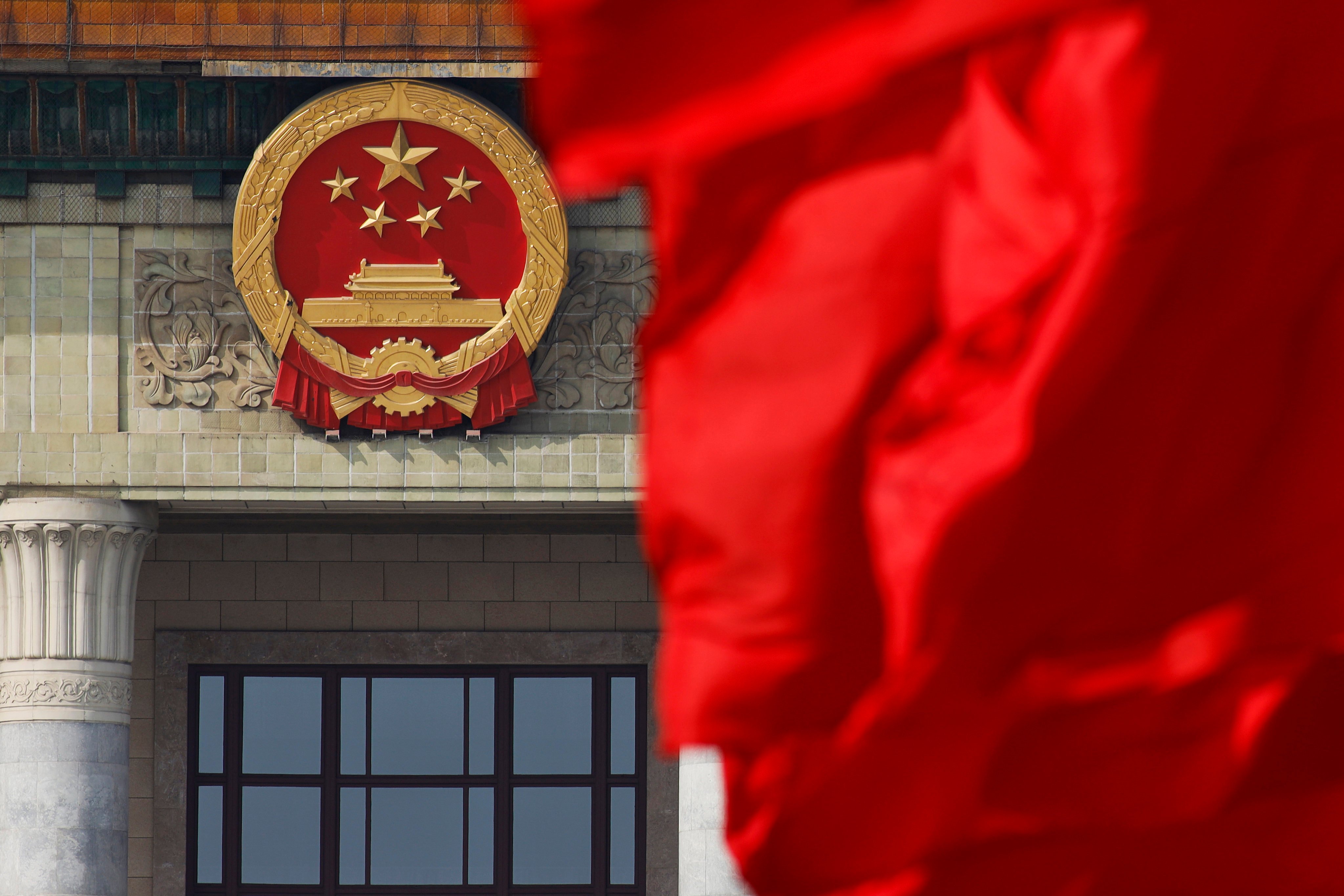 A red flag flutters near China’s national emblem outside the Great Hall of the People in Beijing. Photo: AP