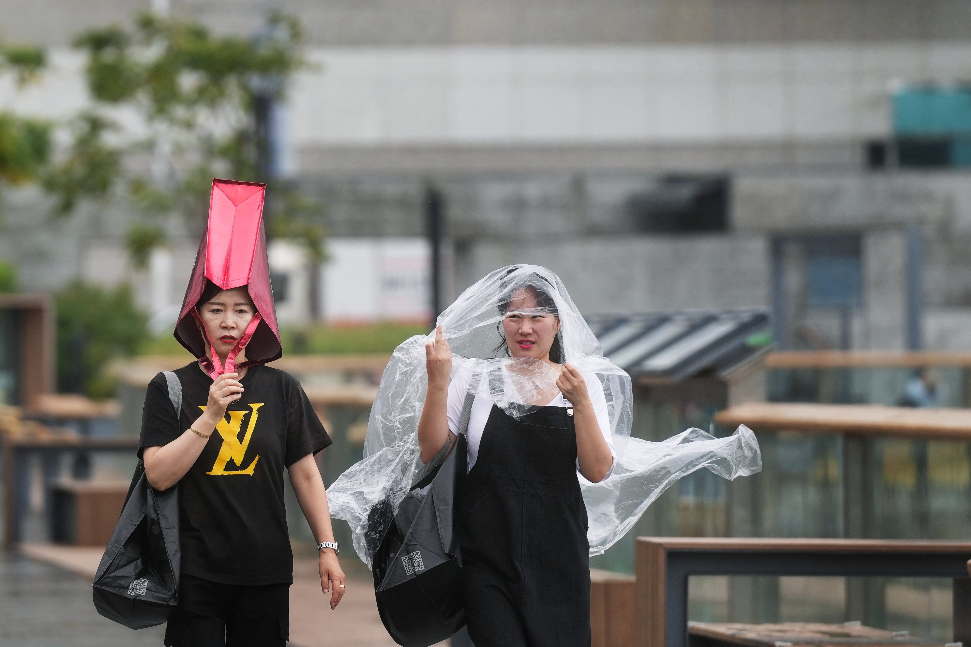 Two women walk along Wan Chai Promenade with a shopping bag and a plastic raincoat covering their heads as Typhoon Toraji edges closer to the coast of southern China on November 13. Photo: Elson Li