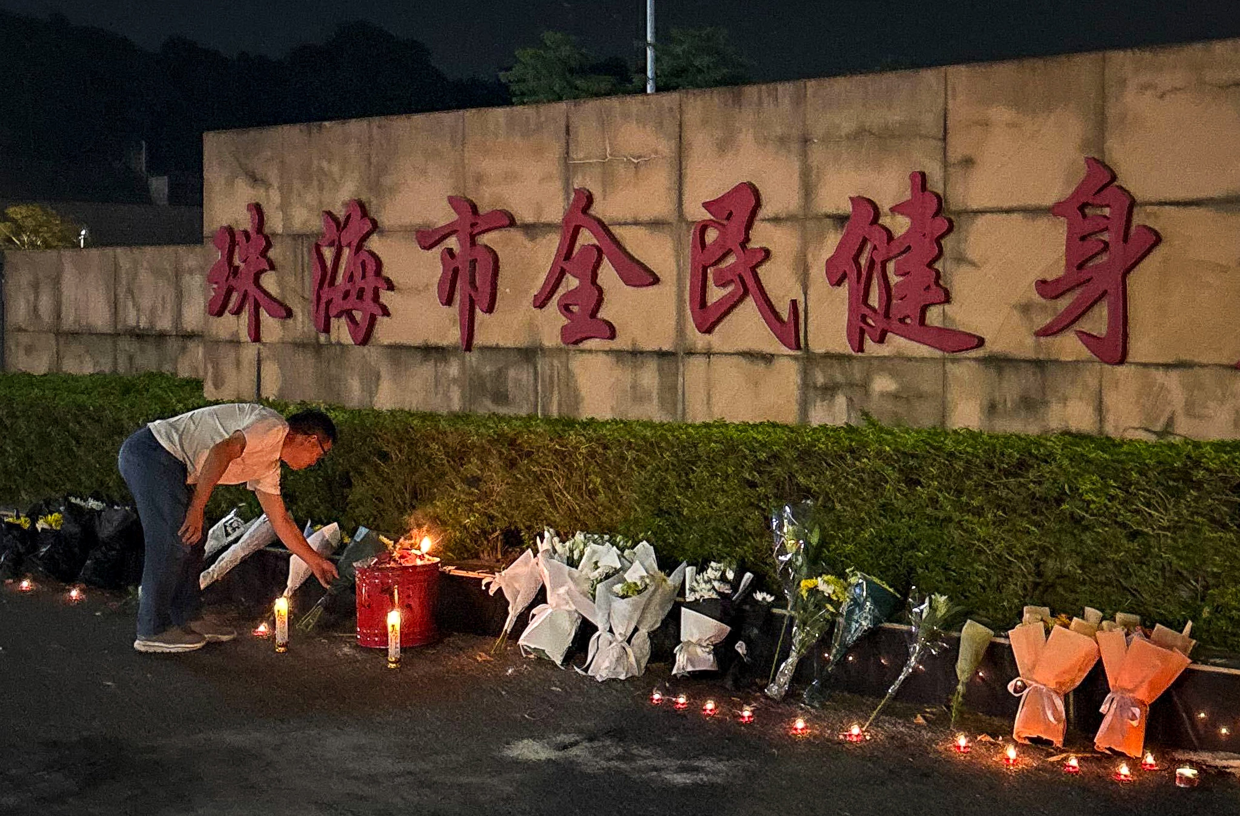 A man looks at candles left outside the Zhuhai Sports Centre, a day after a car drove into a crowd of people exercising there, killing at least 35. Photo: Amber Wang