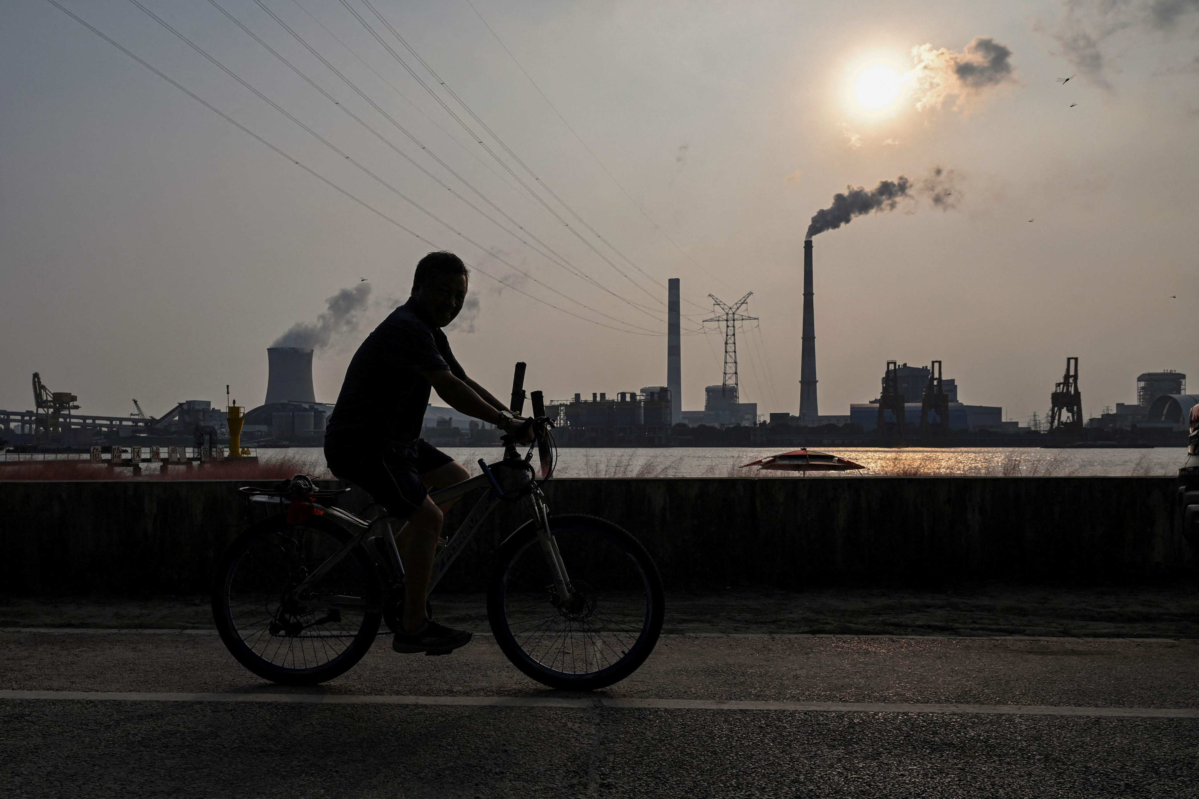 A man rides a bicycle near a power station in Shanghai. File photo: AFP