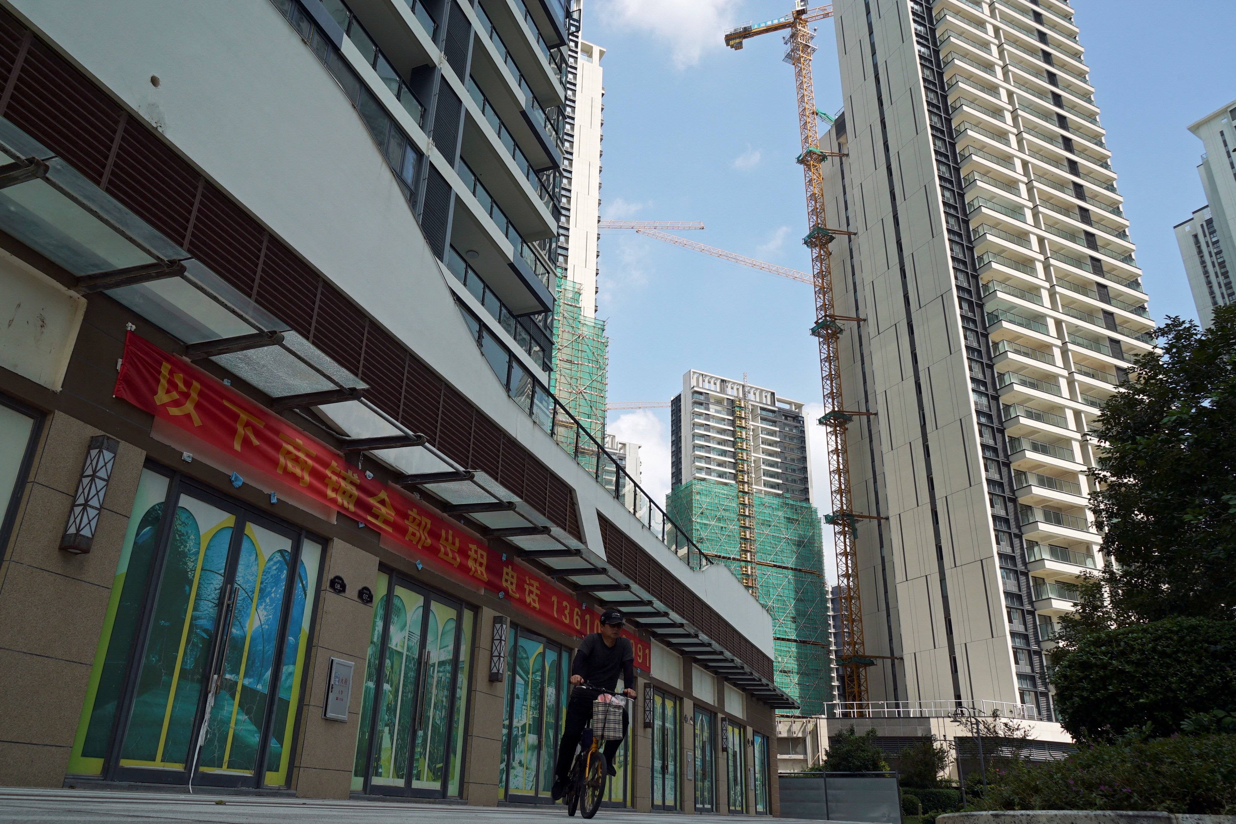 A man rides a bicycle past residential buildings under construction in Huizhou, Guangdong province, on October 10, 2024. Photo: Reuters