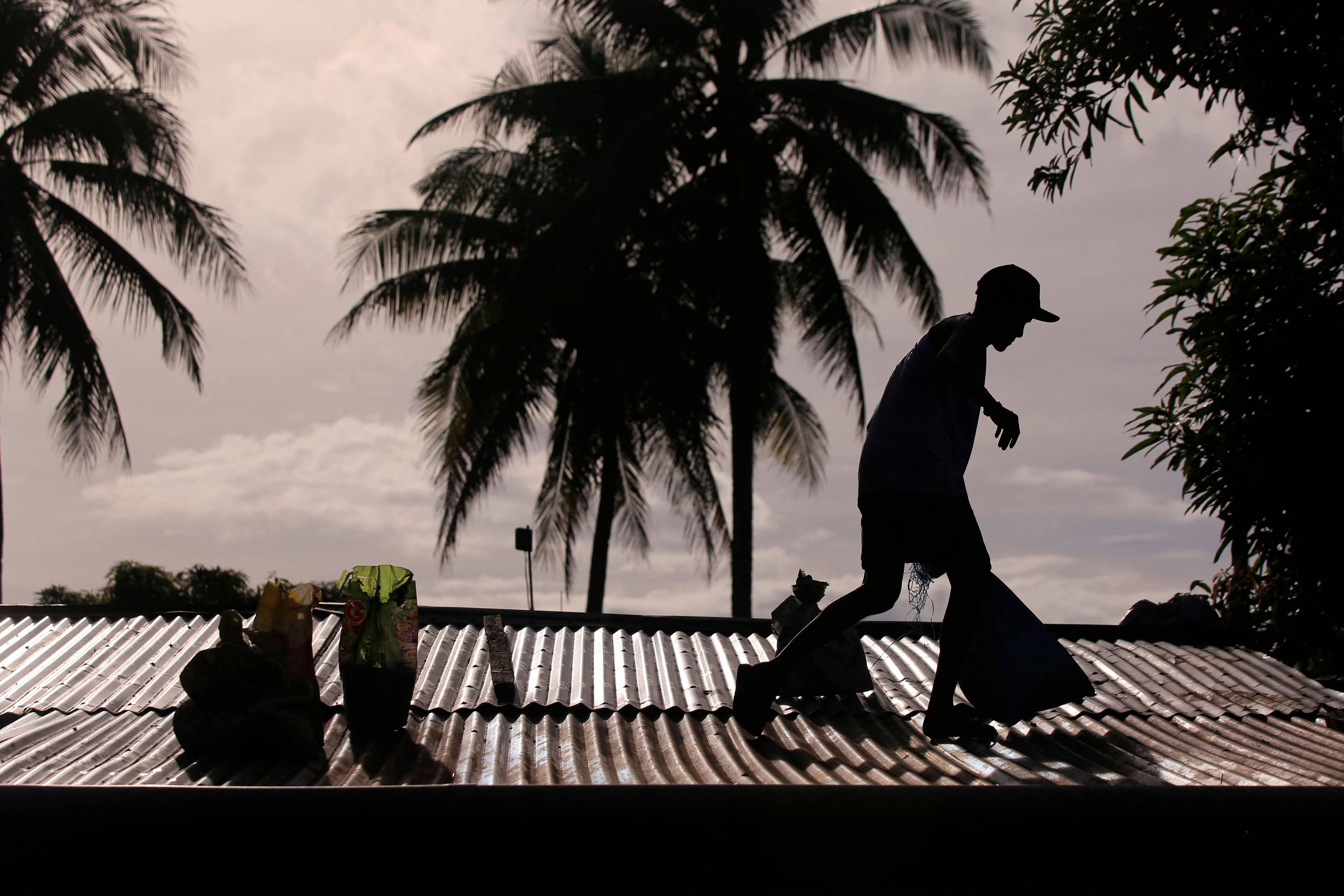 A resident secures the roof of a house in Legazpi City, Albay province, on November 15. Photo: AFP