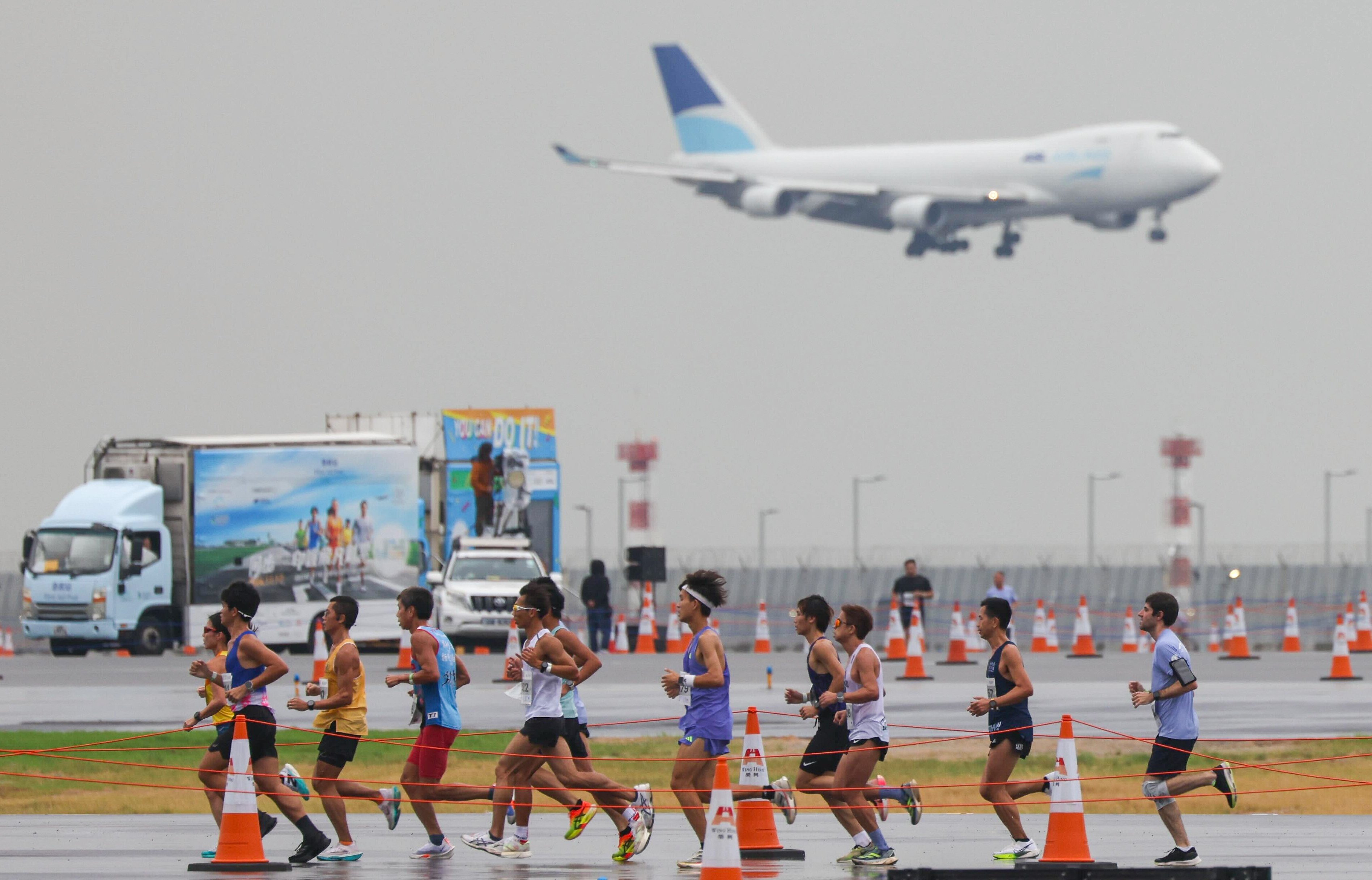 A plane comes into land as runners compete in the Standard Chartered Hong Kong Marathon10km race on the third runway at the city’s international airport. Photo: Eugene Lee