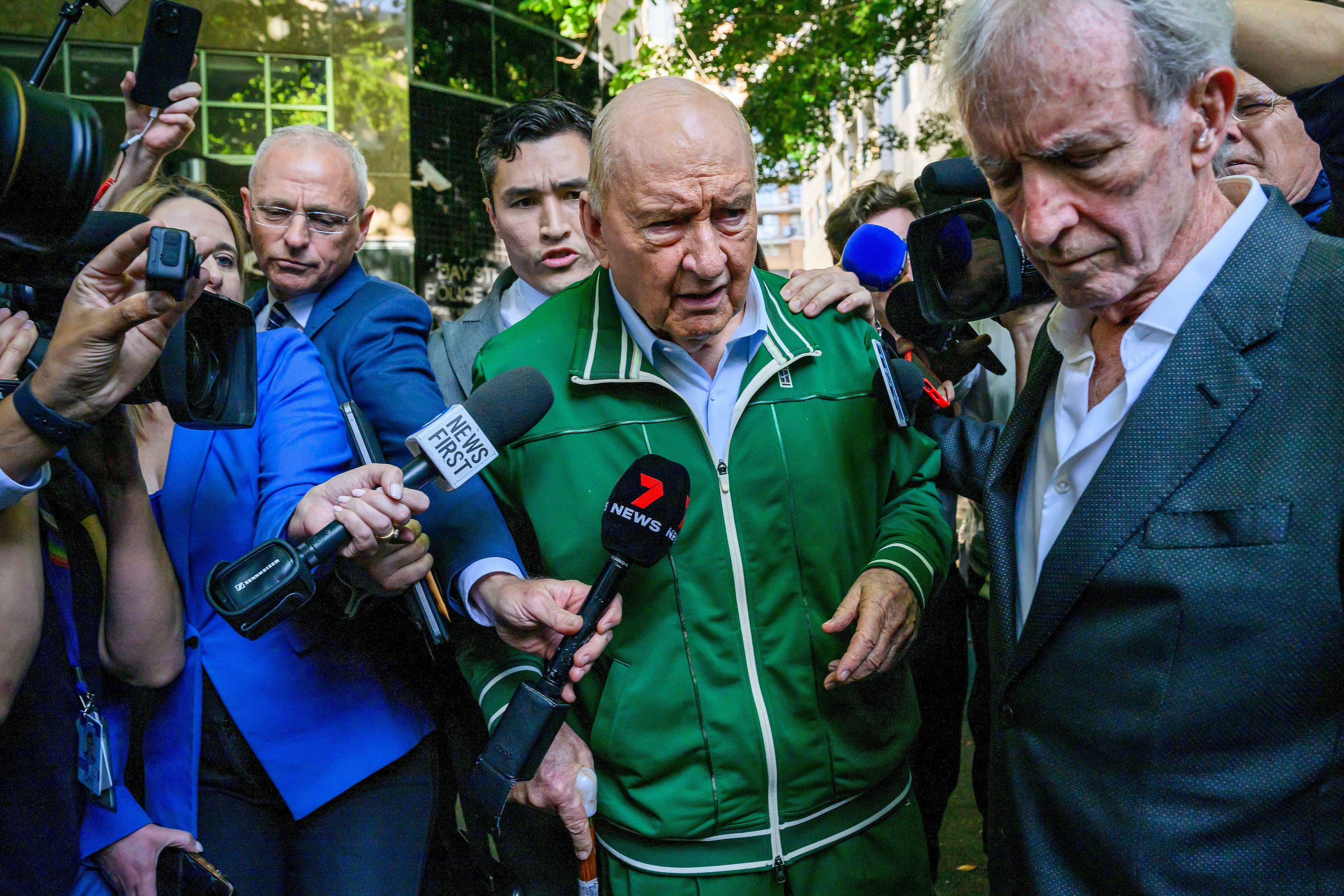 Retired broadcaster Alan Jones (centre) walks past waiting media as he leaves a police station in Sydney on Monday. Photo: AAP Image via AP