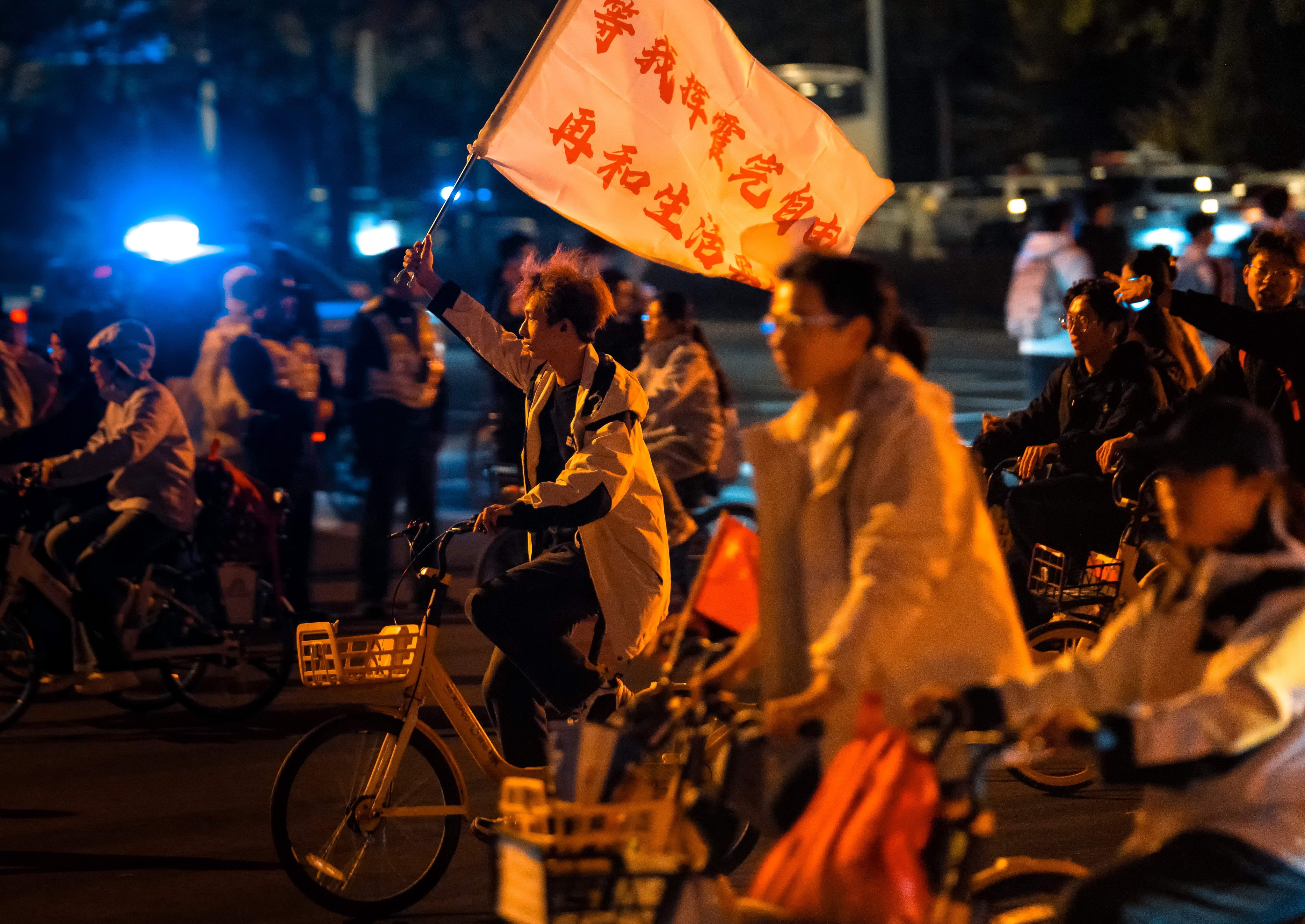 A cyclist waves a flag saying “I will reach a compromise with life after I squander my freedom”, as students ride rental bicycles in Zhengzhou city, Henan province, on November 8. Photo: EPA-EFE