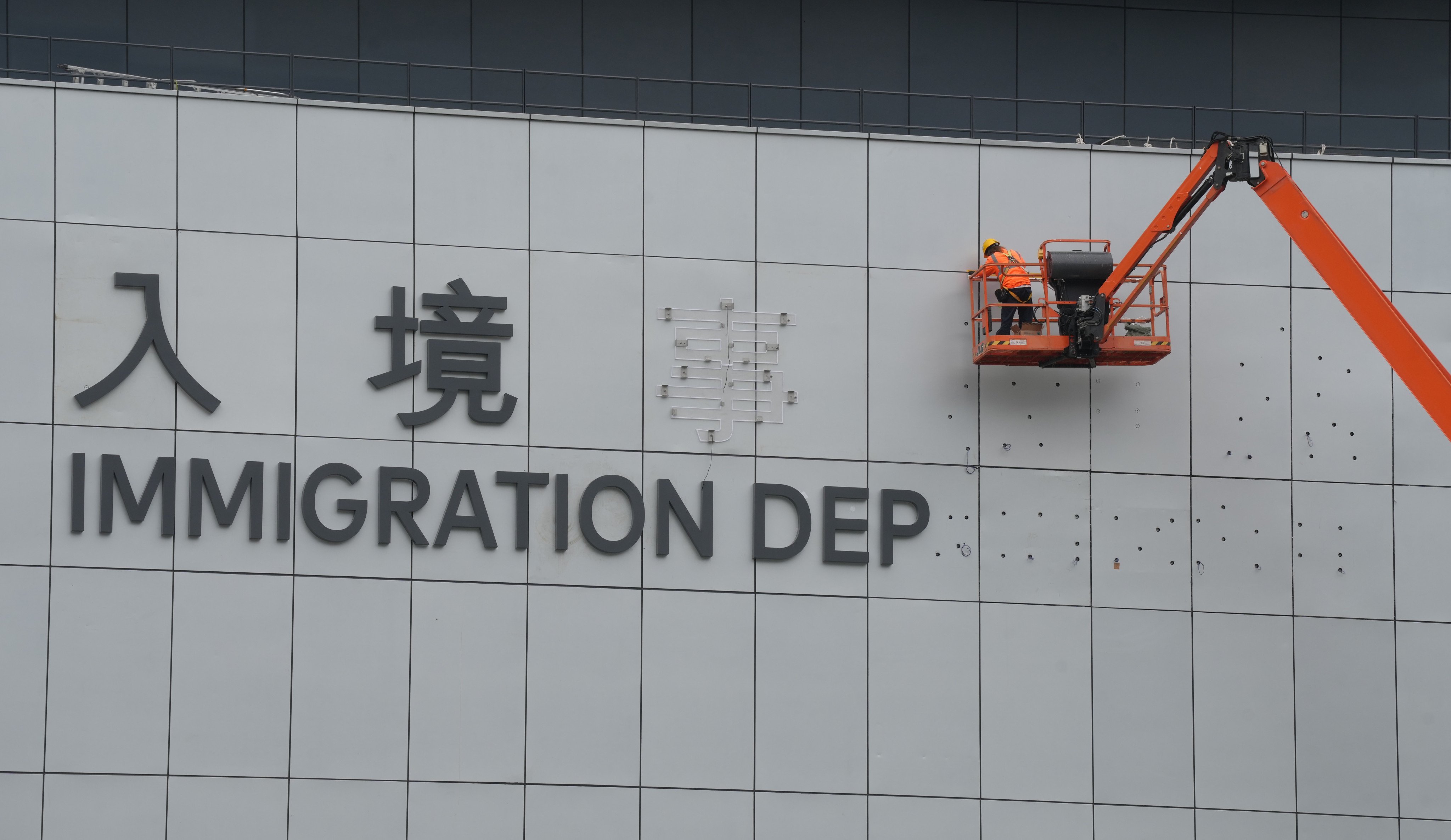 A worker installs the name of the new Immigration Tower in Tseung Kwan O, on January 23. Photo: Elson Li