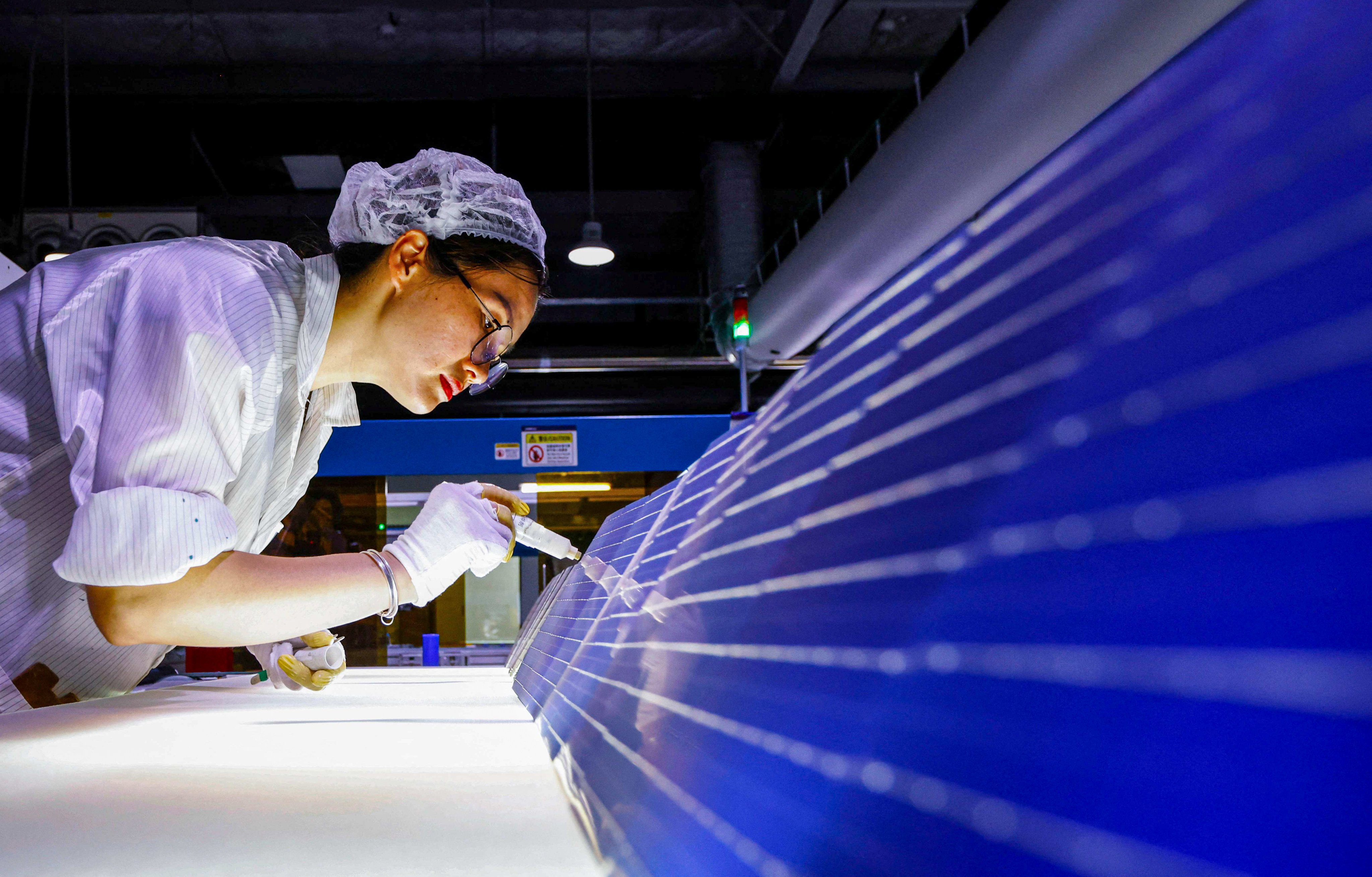 An employee works on solar photovoltaic modules for export at a factory in China’s Jiangsu province. Photo: AFP