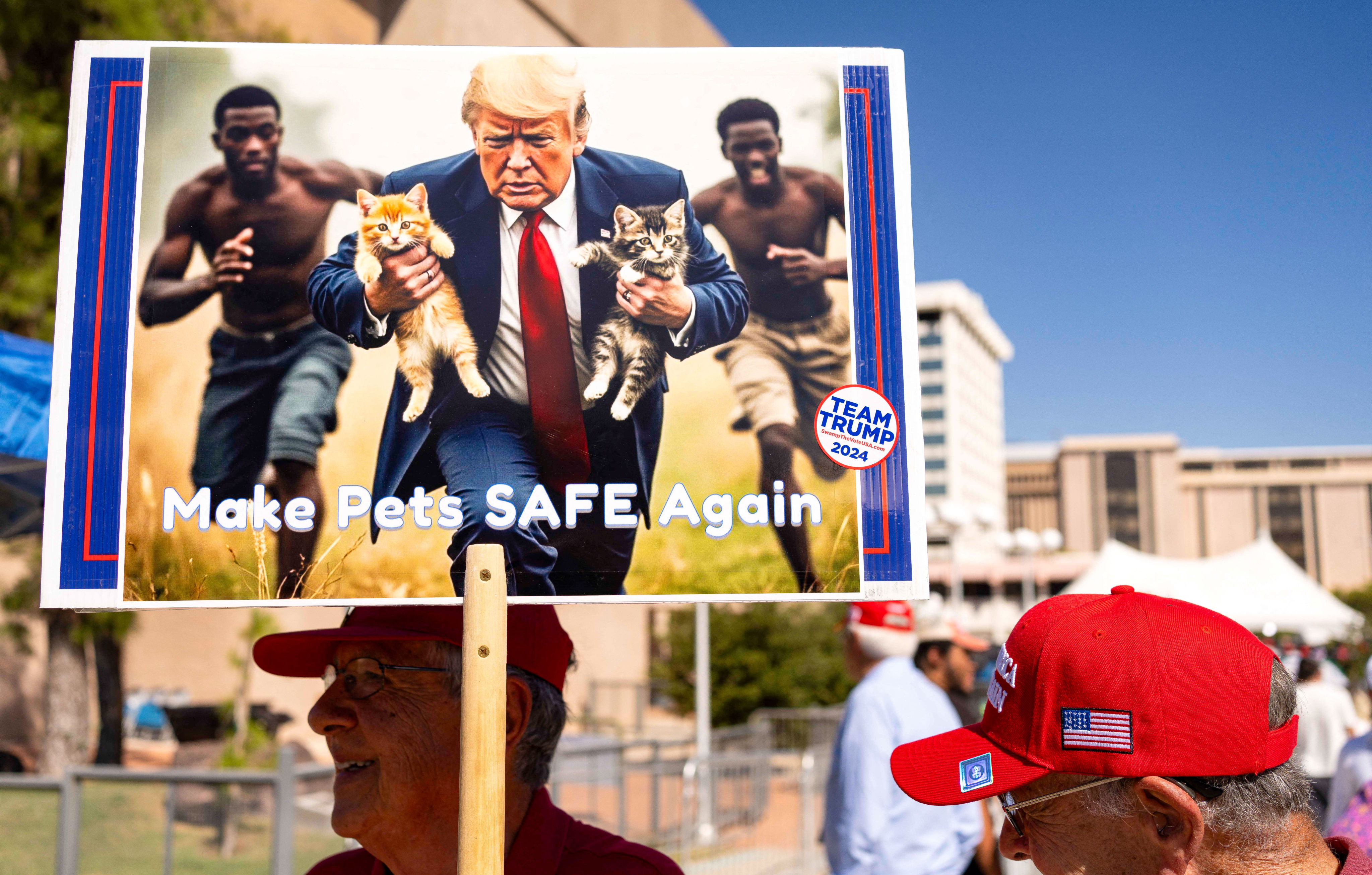 A man carries an AI-generated image of former President and Republican presidential candidate Donald Trump carrying cats away from Haitian immigrants, a reference to falsehoods spread about Springfield, Ohio, during a campaign rally for Trump at the Tucson Music Hall in Tucson, Arizona, Sept. 12, 2024. (Rebecca Noble/AFP/Getty Images/TNS)