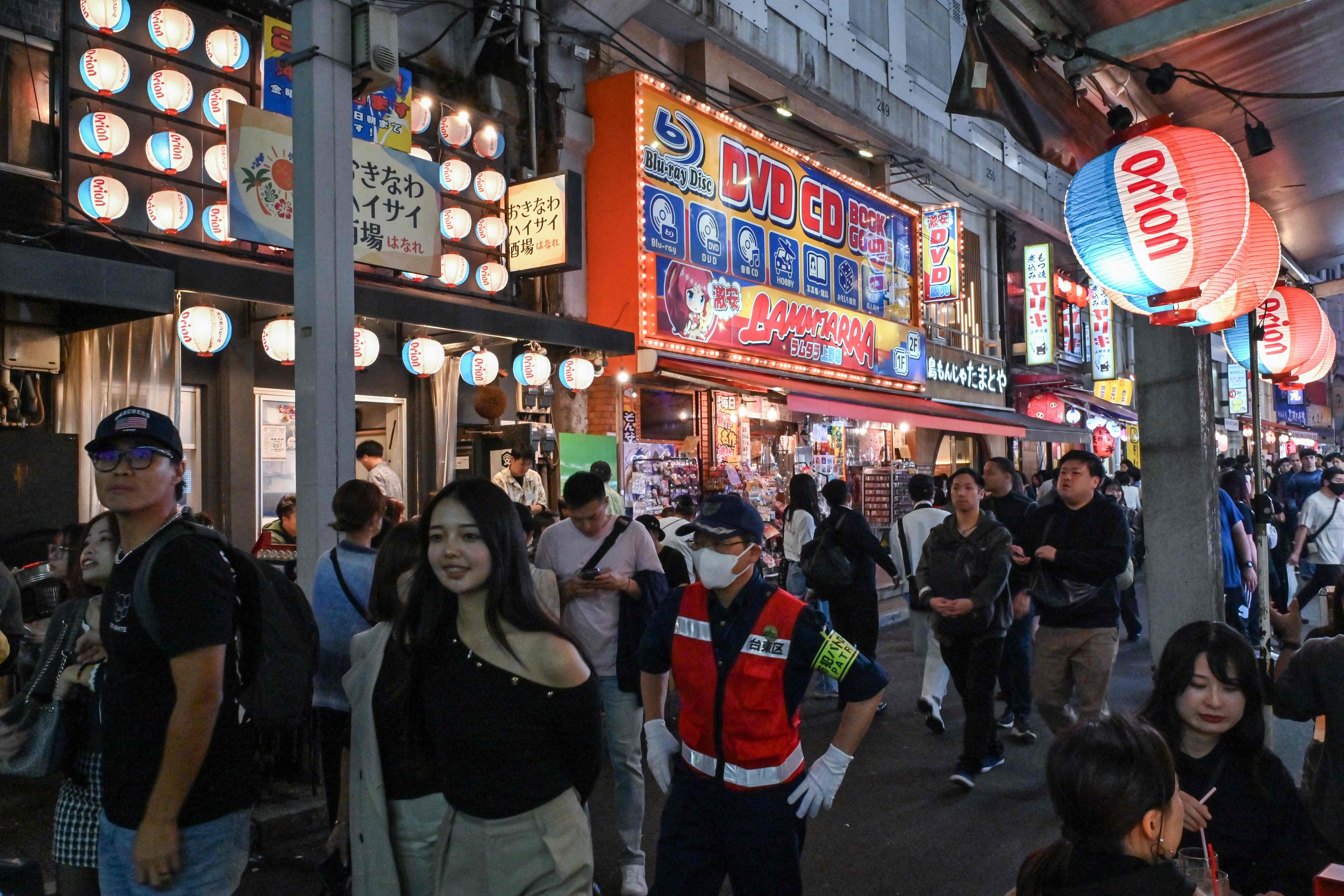 Visitors walk past restaurants in a popular tourist area next to the rail tracks in the Ueno district of central Tokyo on November 17. Photo: AFP