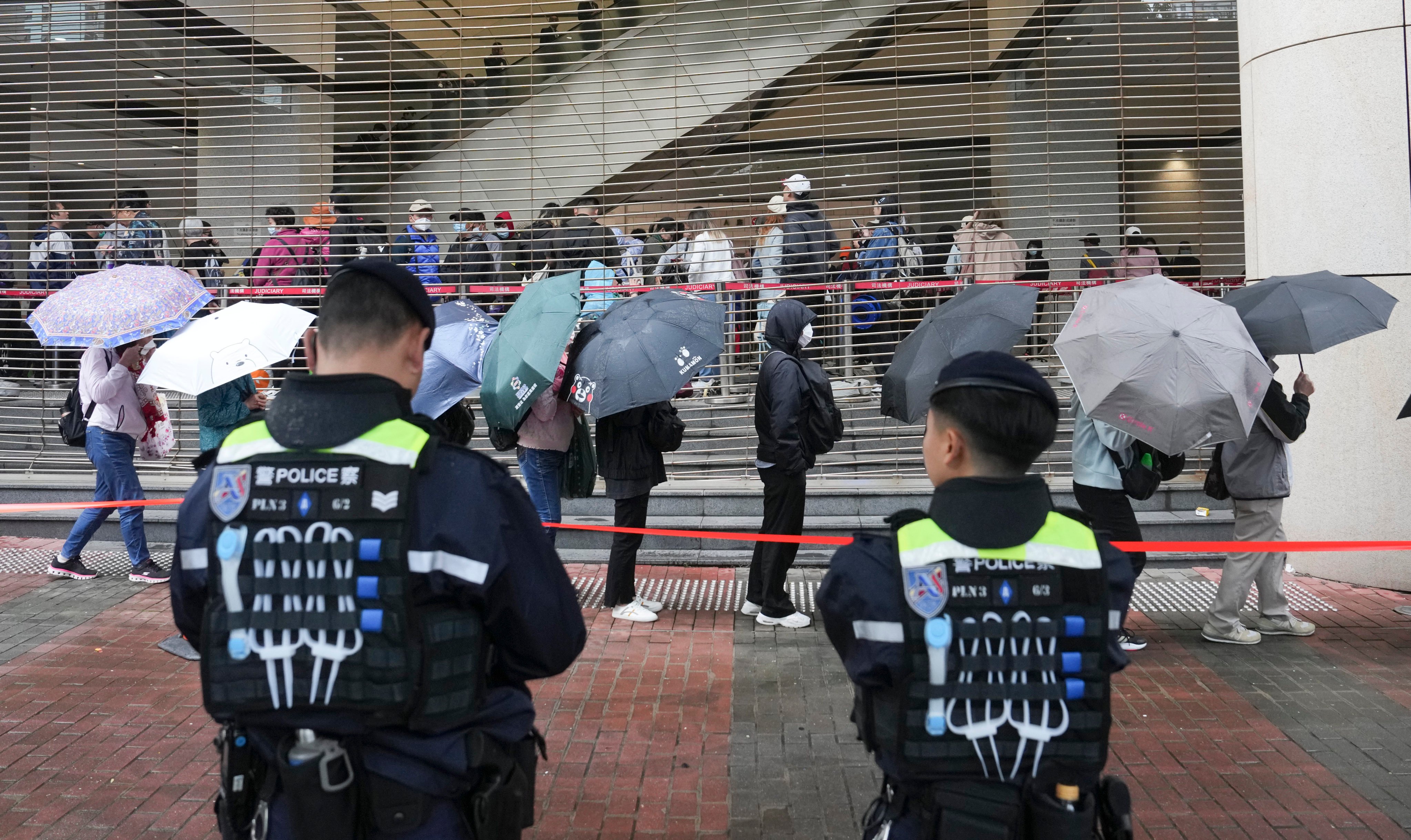 Police stand guard as people line up outside West Kowloon Court on Tuesday. Photo: Elson Li