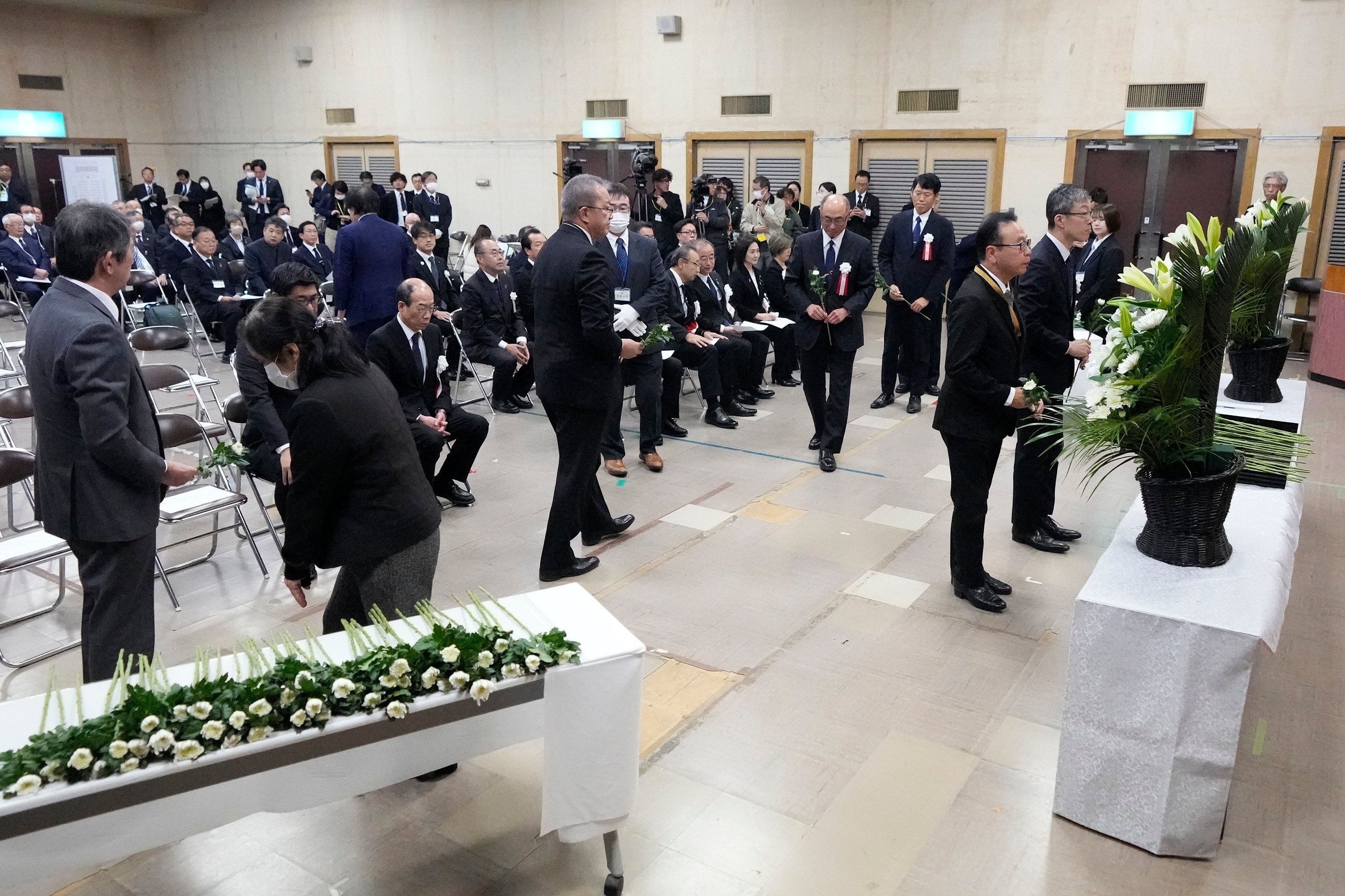 Guests offer a flower during a memorial ceremony for the Sado Island Gold Mine in Sado, Niigata prefecture, Japan as several seats reserved for South Korean delegates remained empty. Photo: AP