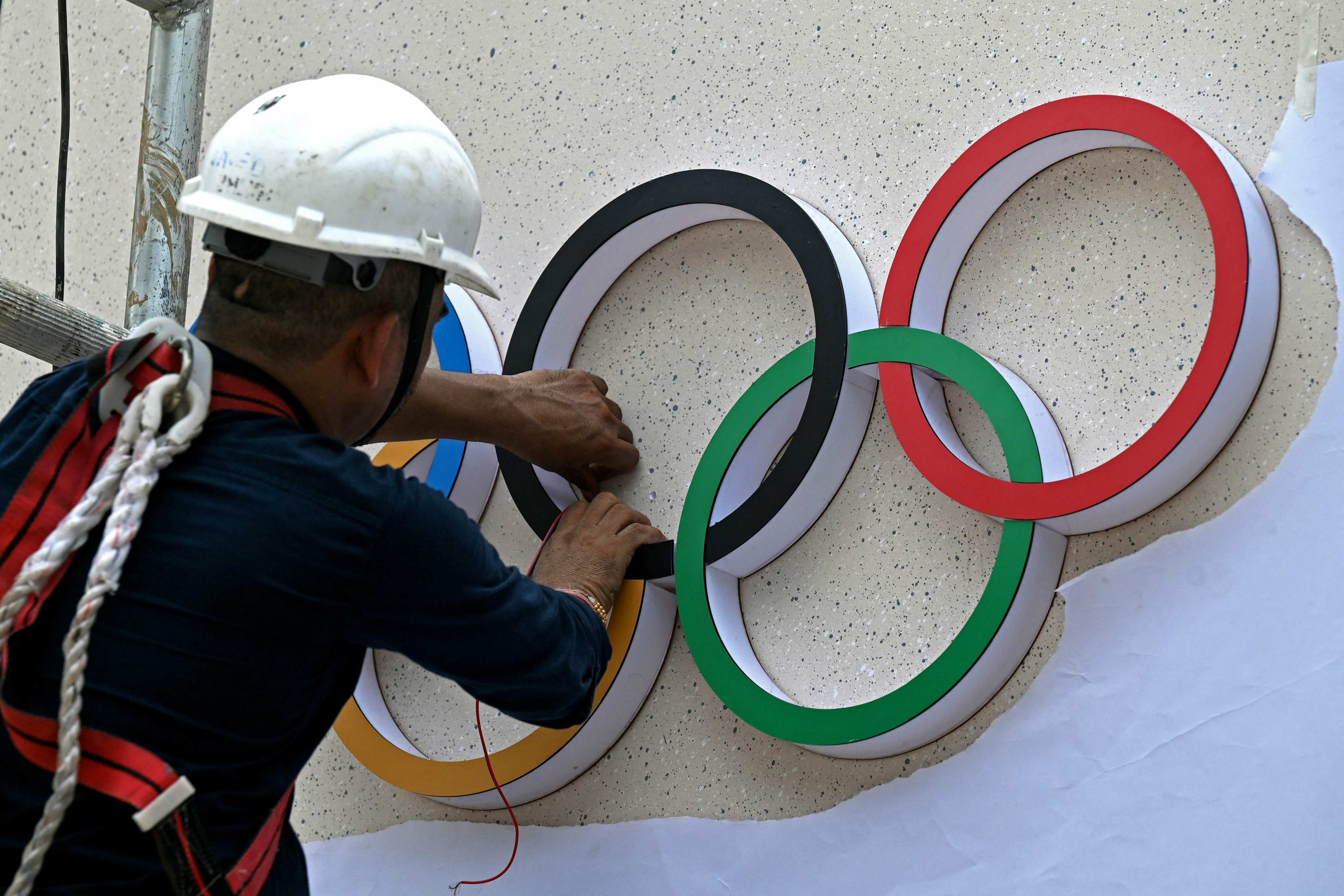 A labourer fixes the Olympic rings at the entrance of a venue ahead of the 141st IOC session in Mumbai in October. Photo: AFP