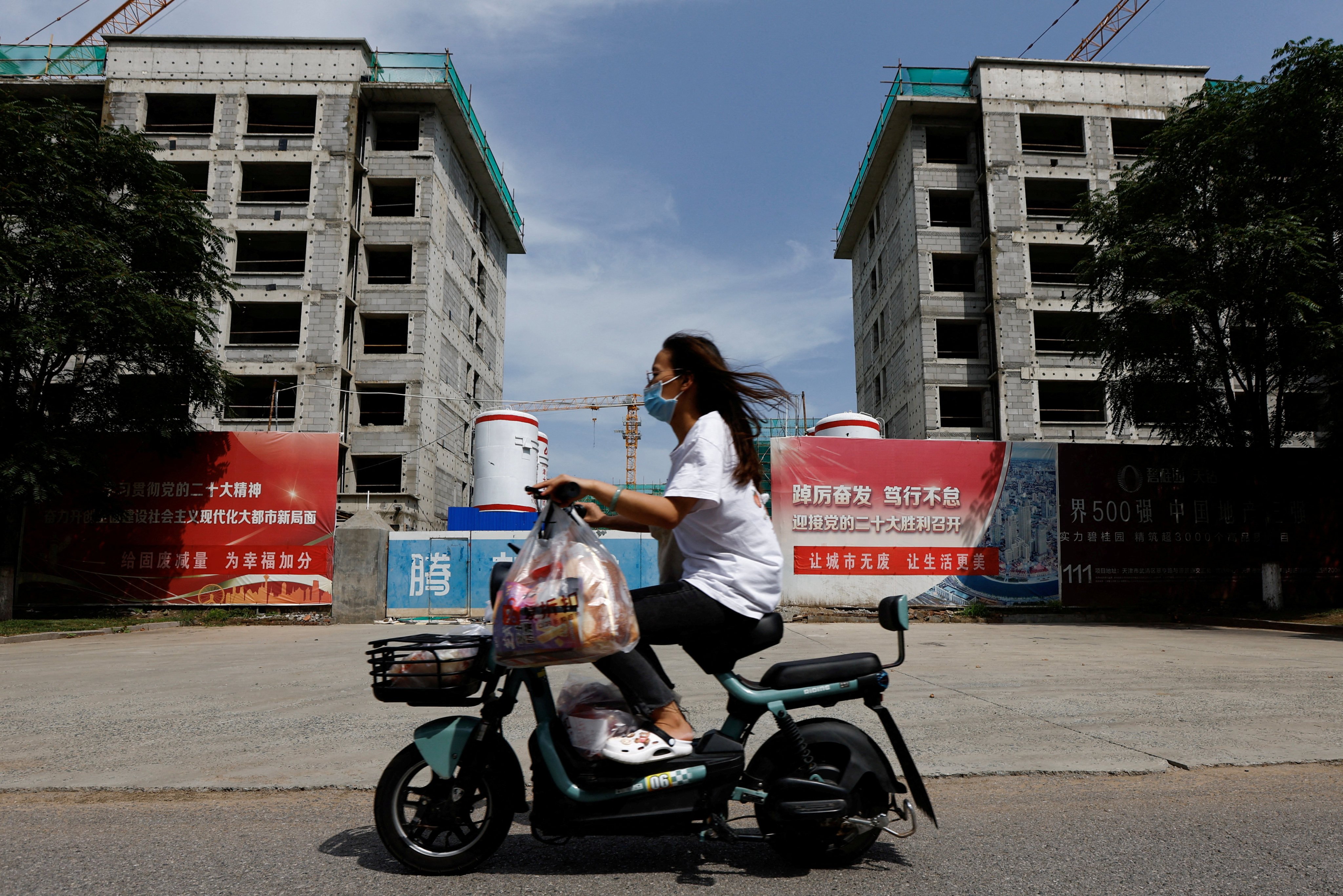 A woman rides a scooter past a construction site of residential buildings by Chinese developer Country Garden, in Tianjin on August 18, 2023. Photo: Reuters