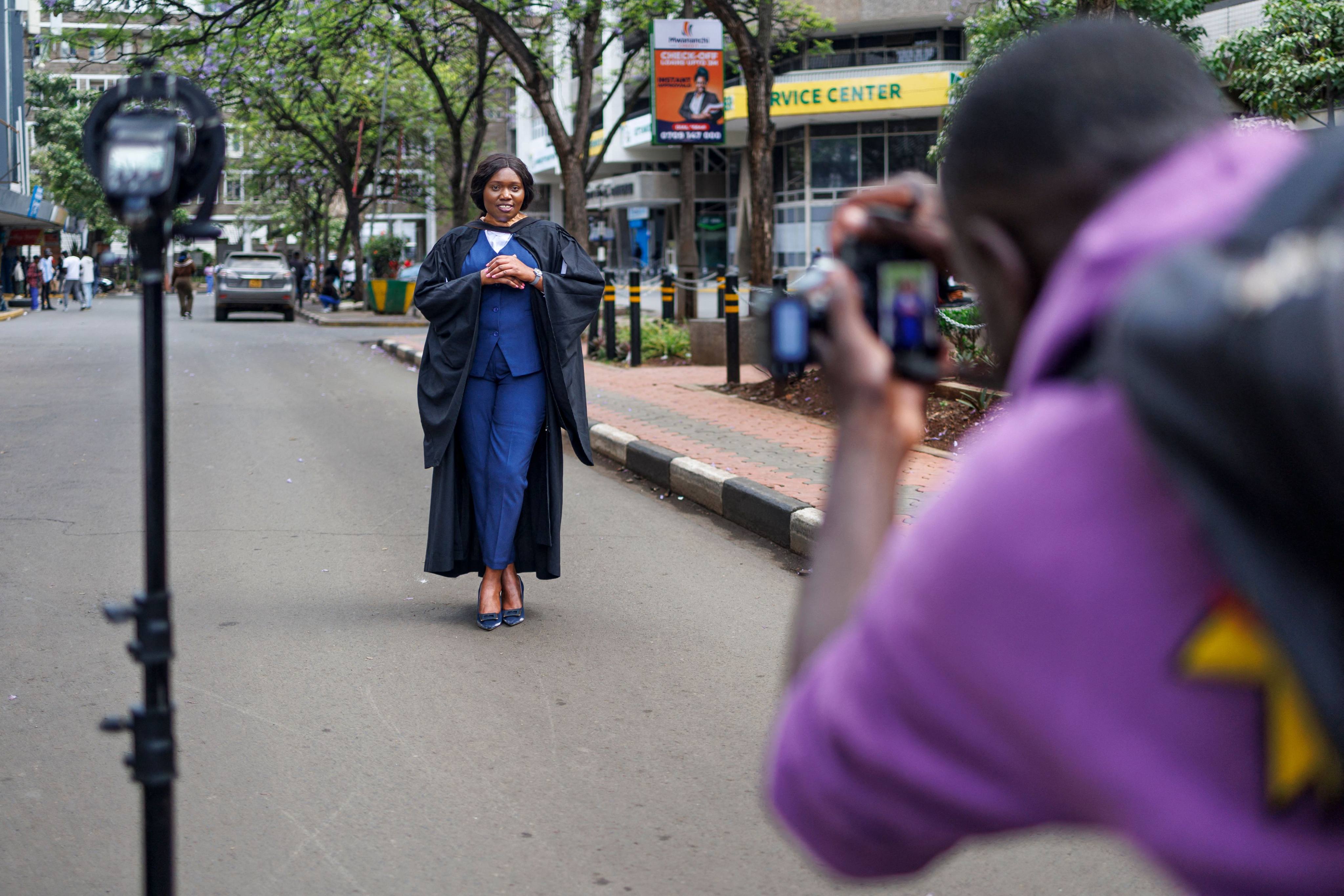 A recent graduate poses in her graduation gown for a street photographer in Nairobi’s central business district. Photo: AFP