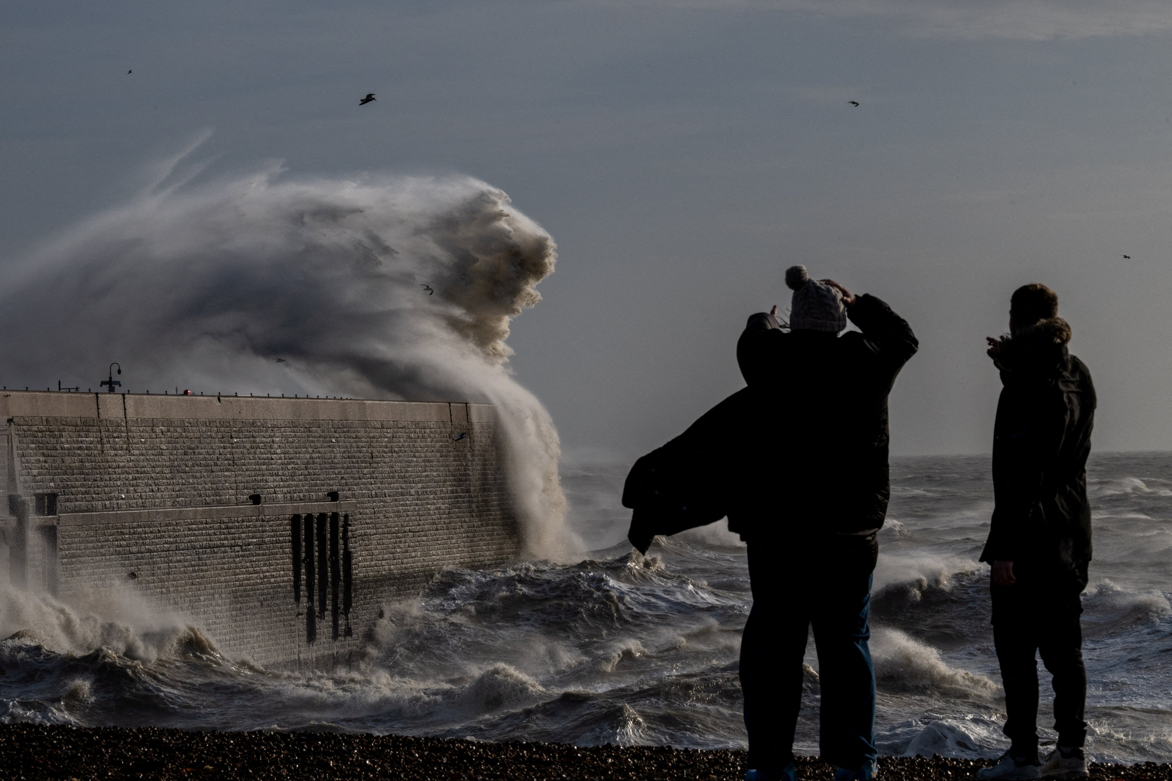 Locals look on as high winds from Storm Bert cause waves to crash over the harbour arm in Folkestone, Britain. Photo: Reuters