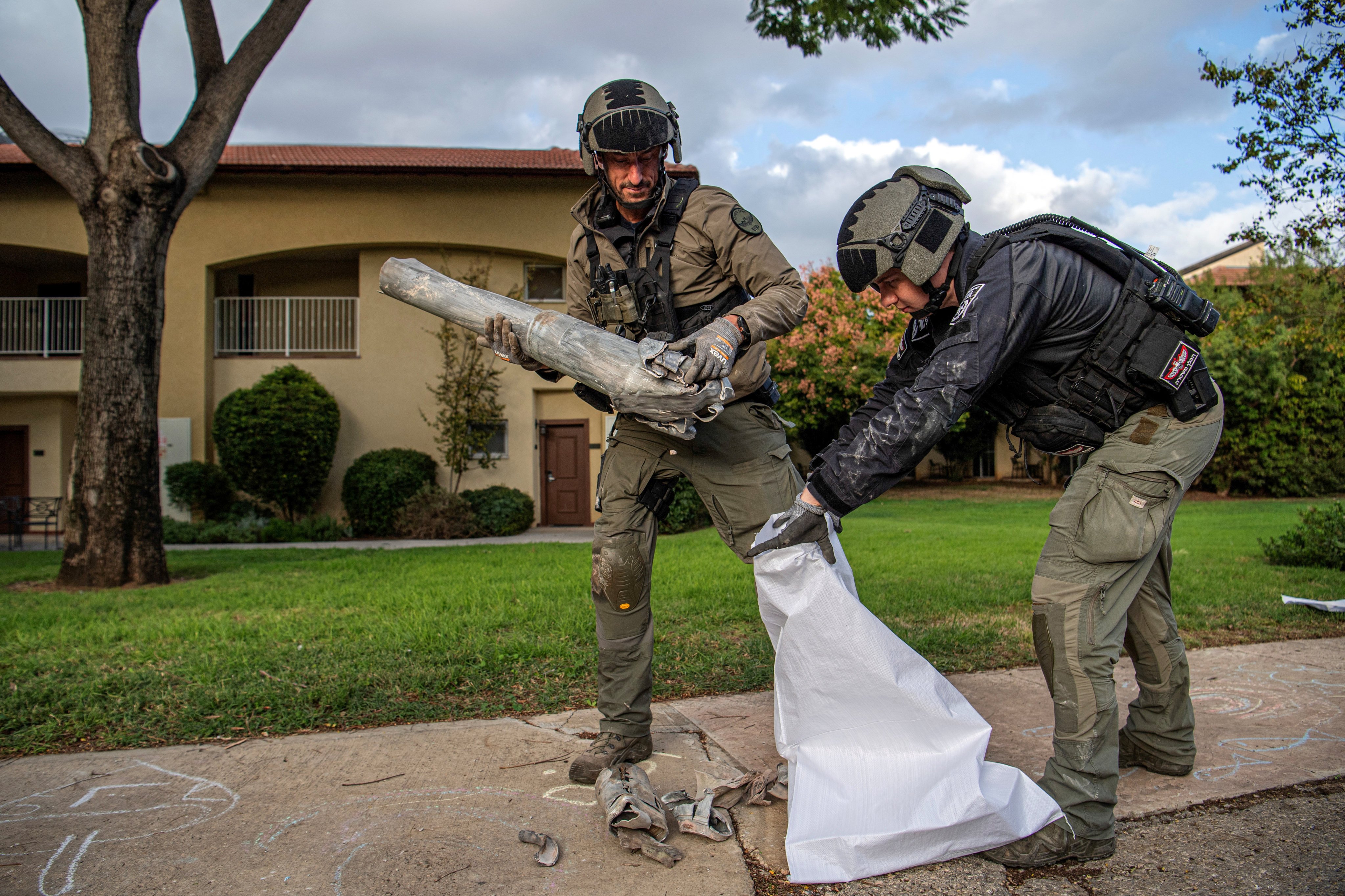 Israeli explosive experts collect part of a projectile that landed in a Kibbutz in northern Israel. Photo: Reuters