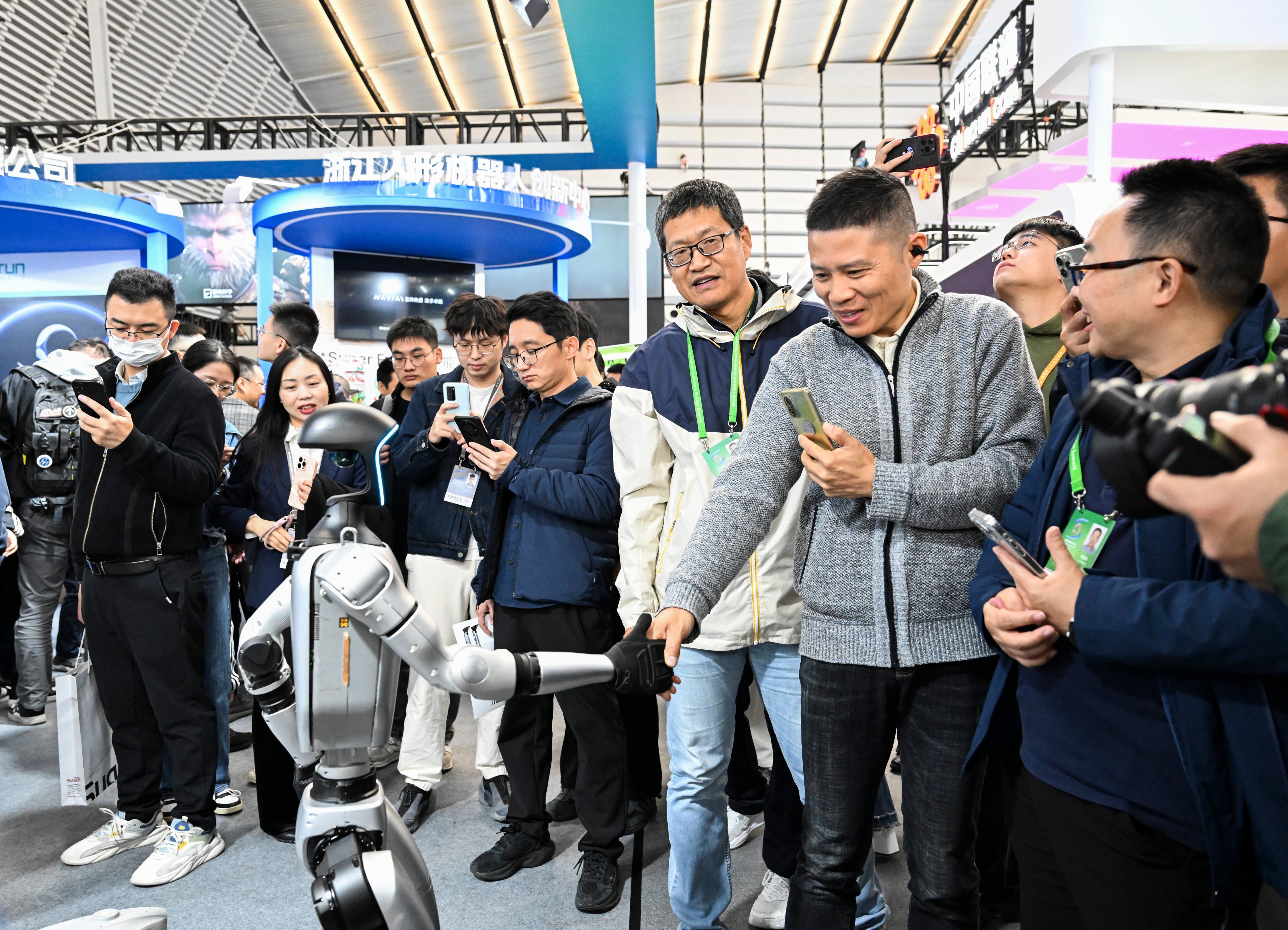 A visitor shakes hands with a humanoid robot at the Light of Internet Expo in Wuzhen, east China’s Zhejiang province. Photo: Xinhua