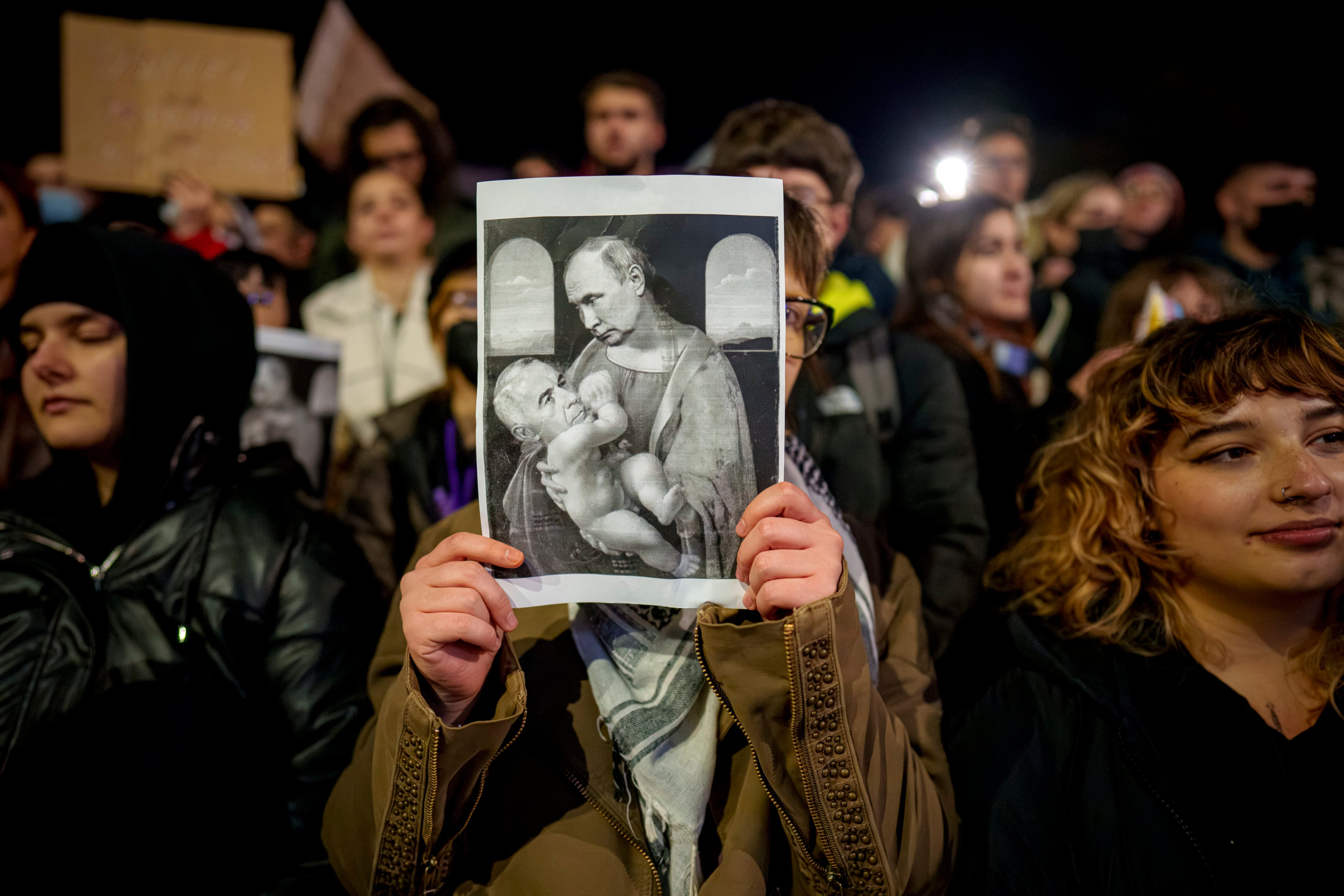 A woman holds an altered version of a classic painting, depicting Russian President Vladimir Putin and Calin Georgescu. Photo: AP