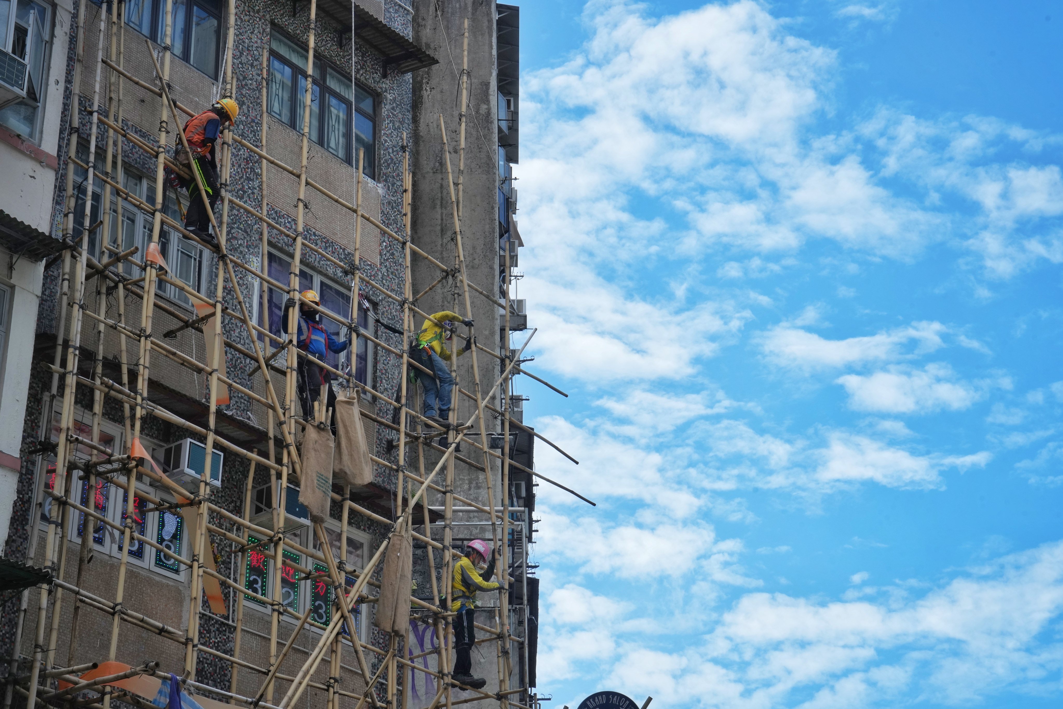 Construction workers remove the bamboo scaffolding of a building in Hong Kong’s Mong Kok district on October 16. As far as possible, drones and robots must be deployed to replace humans in risky operations. Elson Li