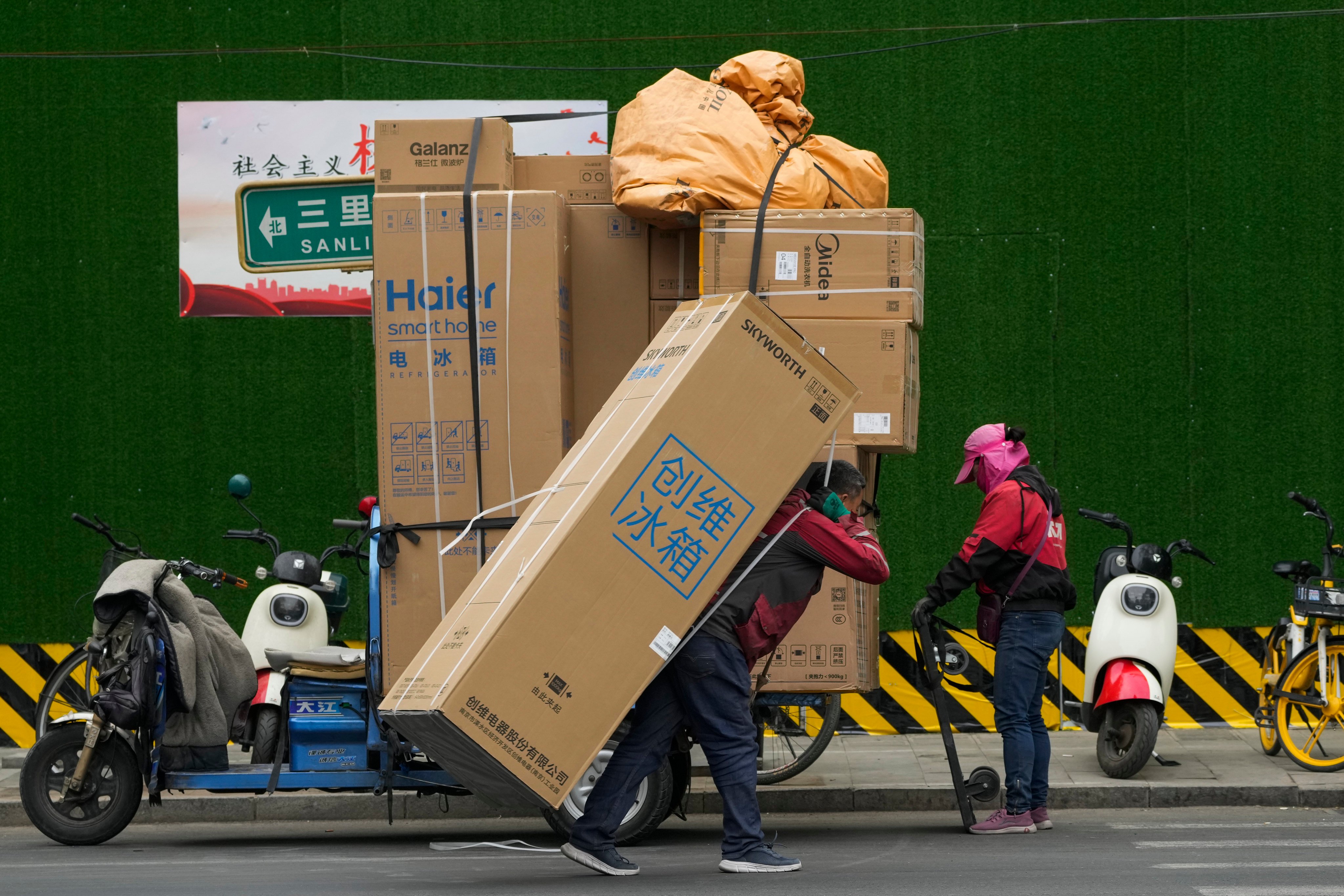 A delivery worker transfers a refrigerator for his customer on a street in Beijing. Photo