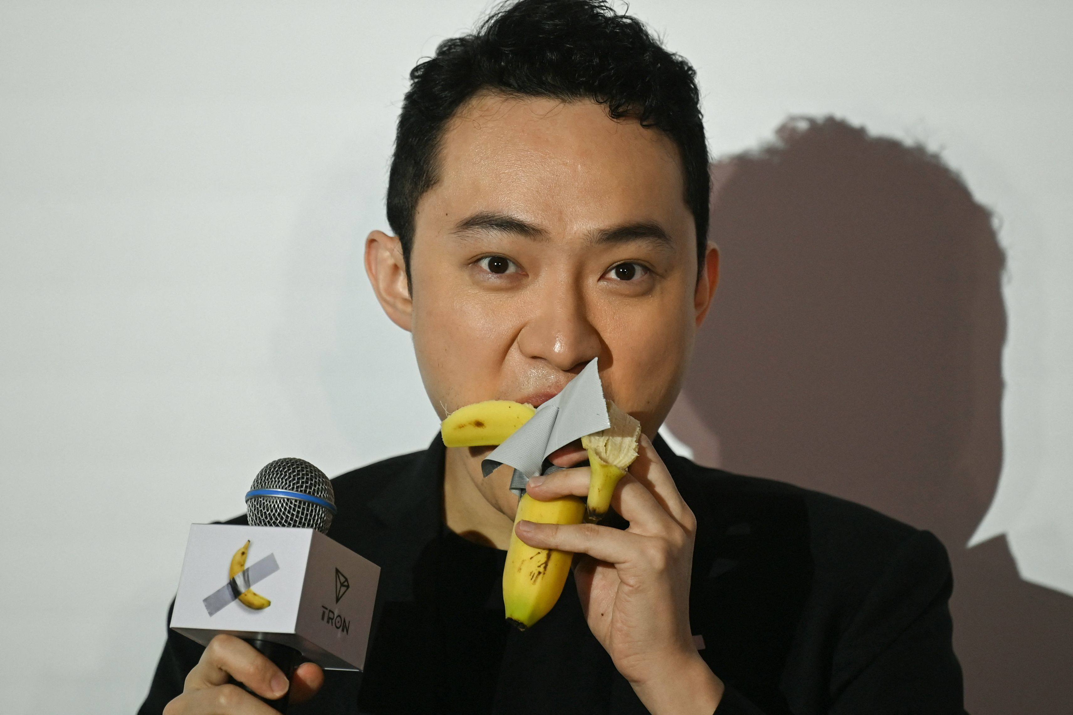 Chinese-born cryptocurrency founder Justin Sun eats a banana artwork, composed of a fresh banana stuck to a wall with duct tape, in Hong Kong on November 29, 2024, a week after buying the provocative work of conceptual art at a New York auction for US$6.2 million. Photo: AFP