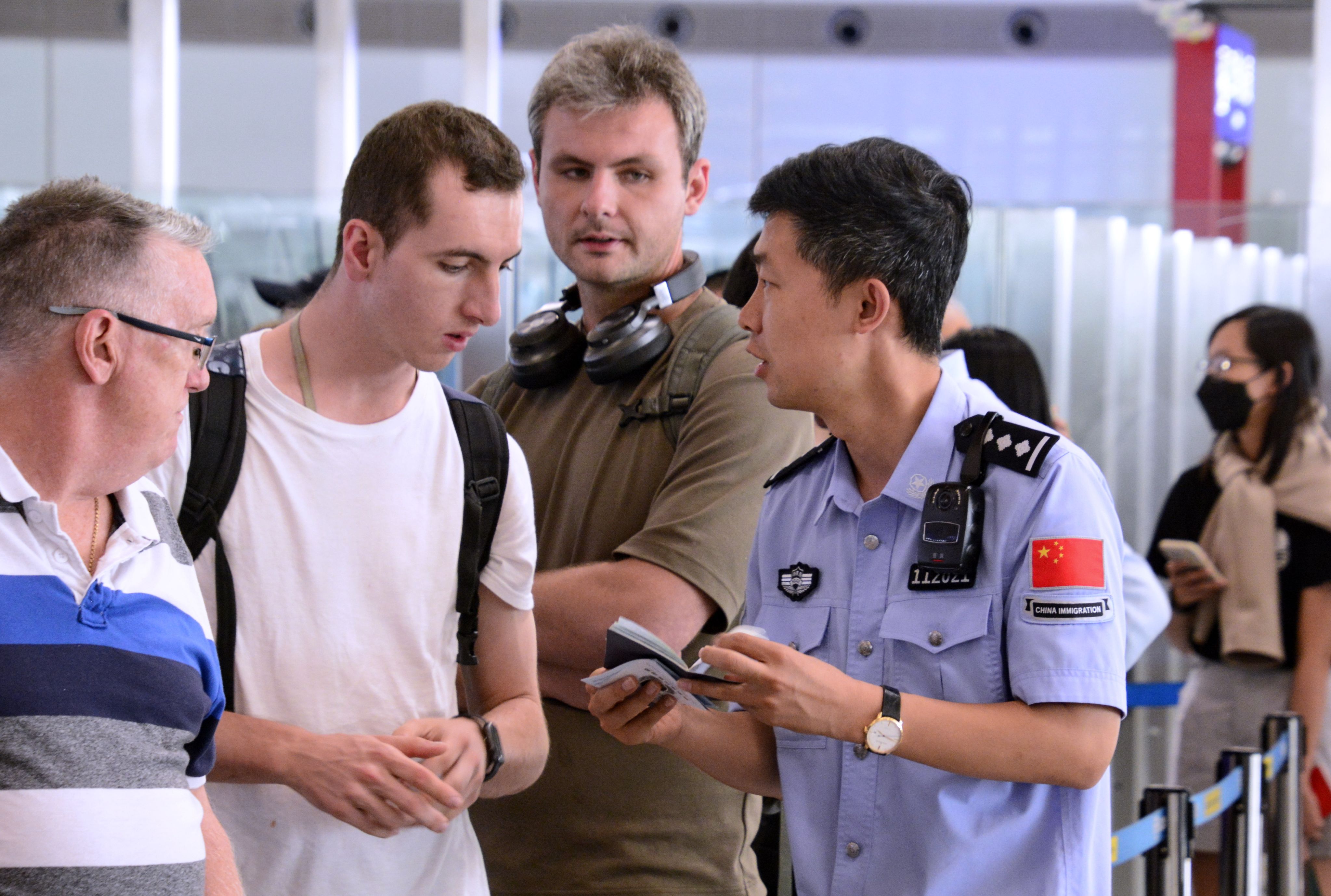 An immigration officer answers foreign visitors’ questions about visa-free entry permits at Beijing Capital International Airport in July. Photo: Xinhua