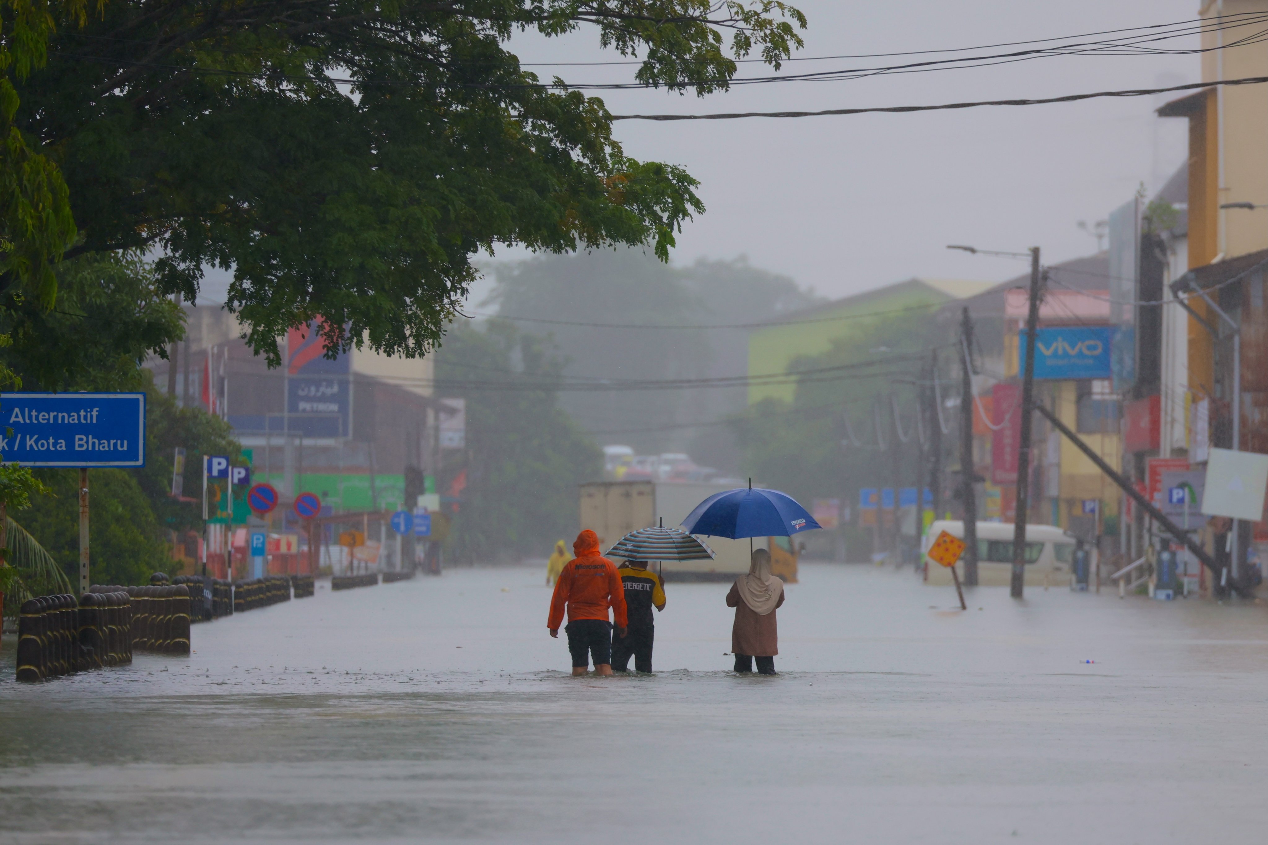 A family wades through flood waters in Pasir Puteh, in Kelantan state, Malaysia, on Saturday. Photo: AFP