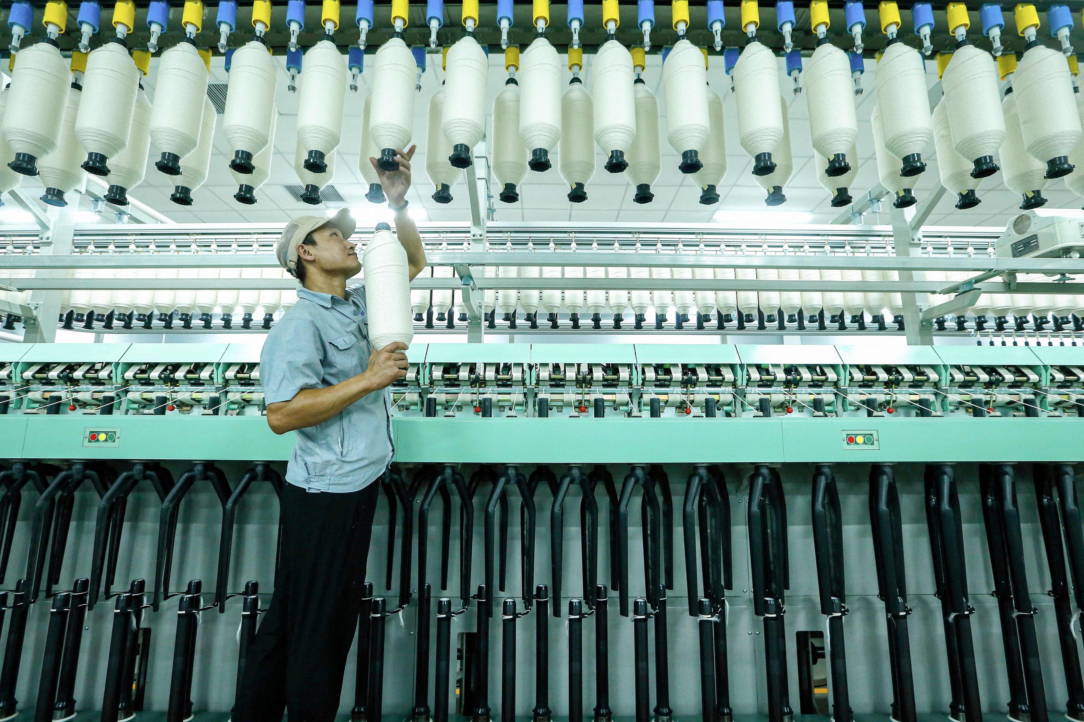 An employee works on a synthetic fiber production line at a textile factory in Qingdao, in China’s eastern Shandong province. Photo: AFP