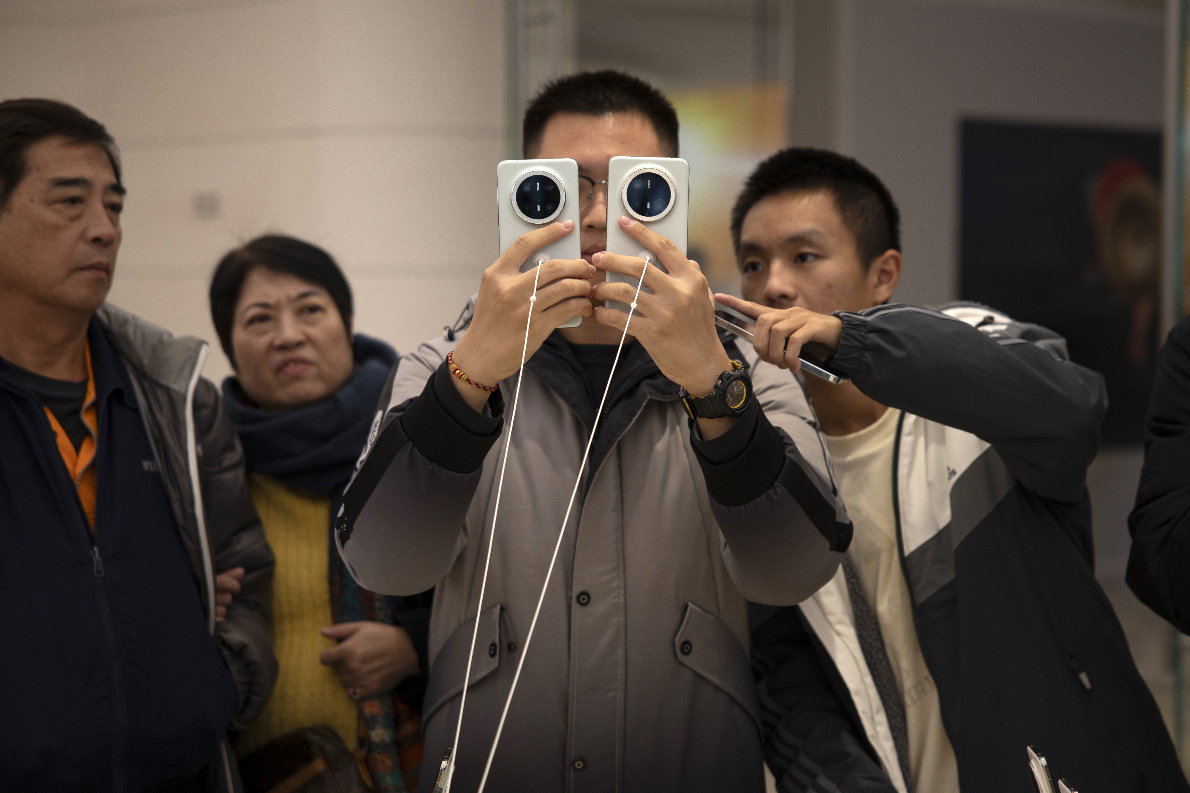 Visitors closely check Huawei Technologies’ new Mate 70-series smartphones at a store in Beijing on November 26, 2024. Photo: EPA-EFE