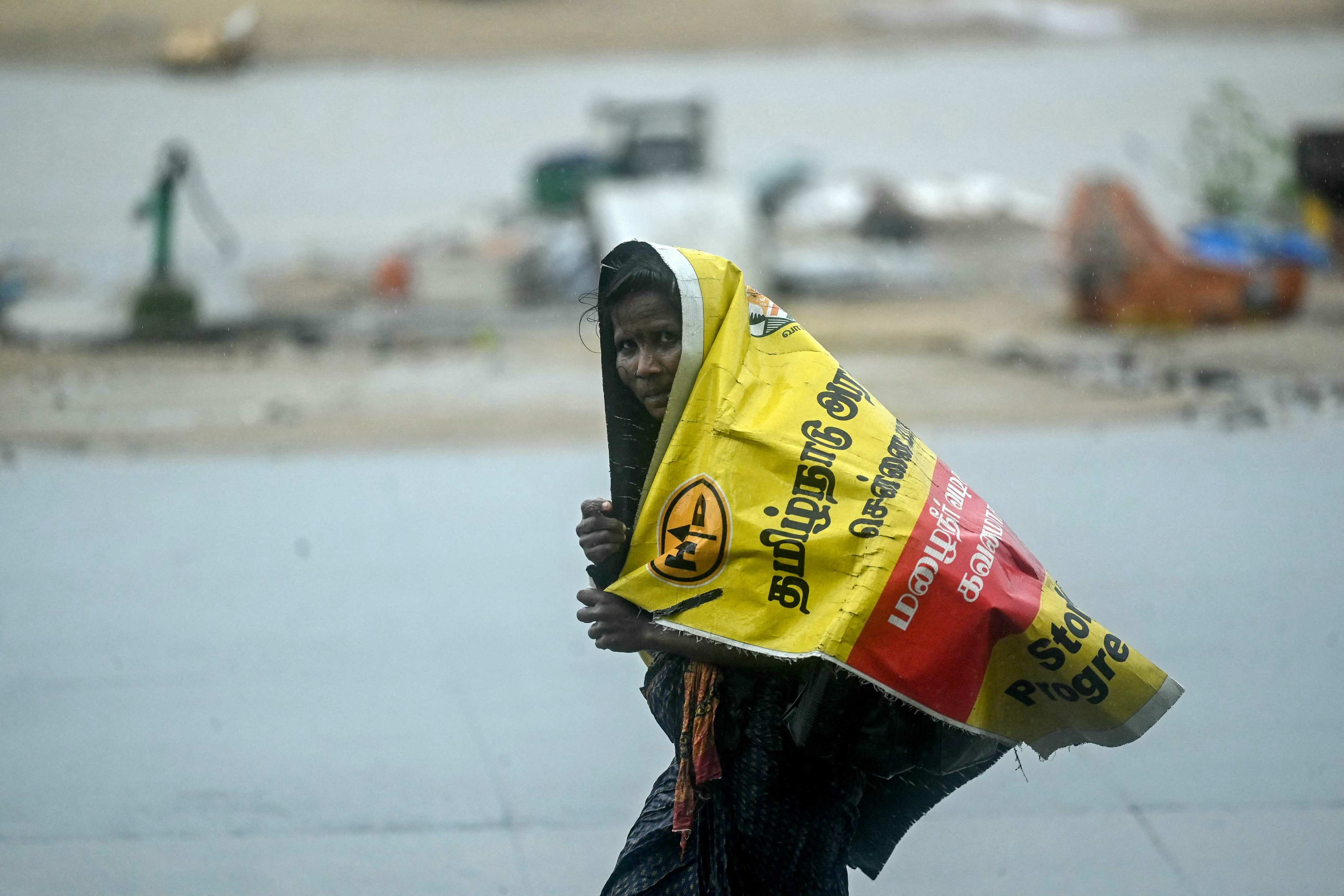 A woman walks in Chennai, India amid heavy wind and rainfall on Saturday, ahead of the landfall of Cyclone Fengal. Photo: AFP