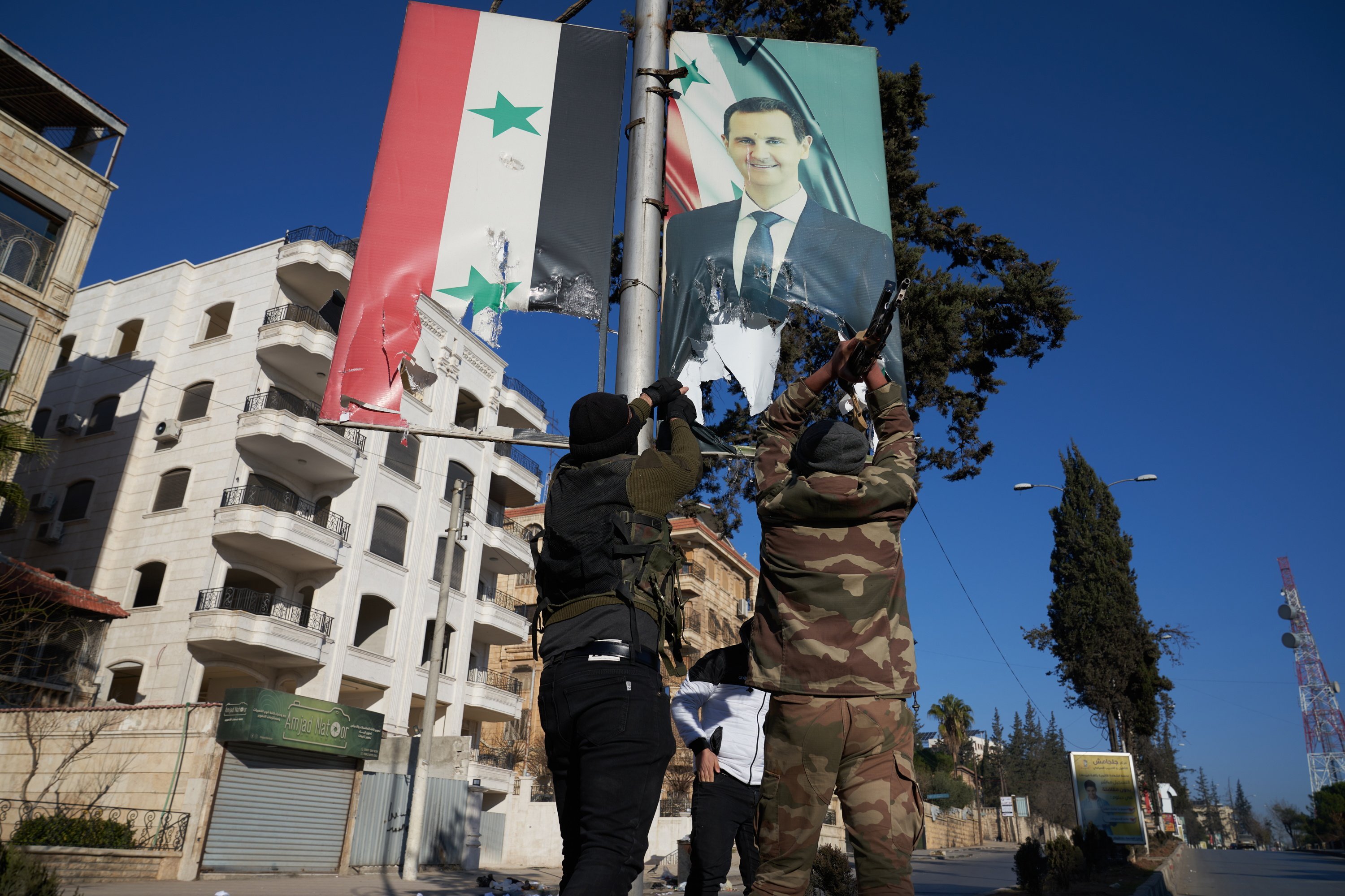 Syrian opposition fighters tear up a portrait of Syrian President Bashar al-Assad in central Aleppo on November 30, 2024. Photo: EPA-EFE