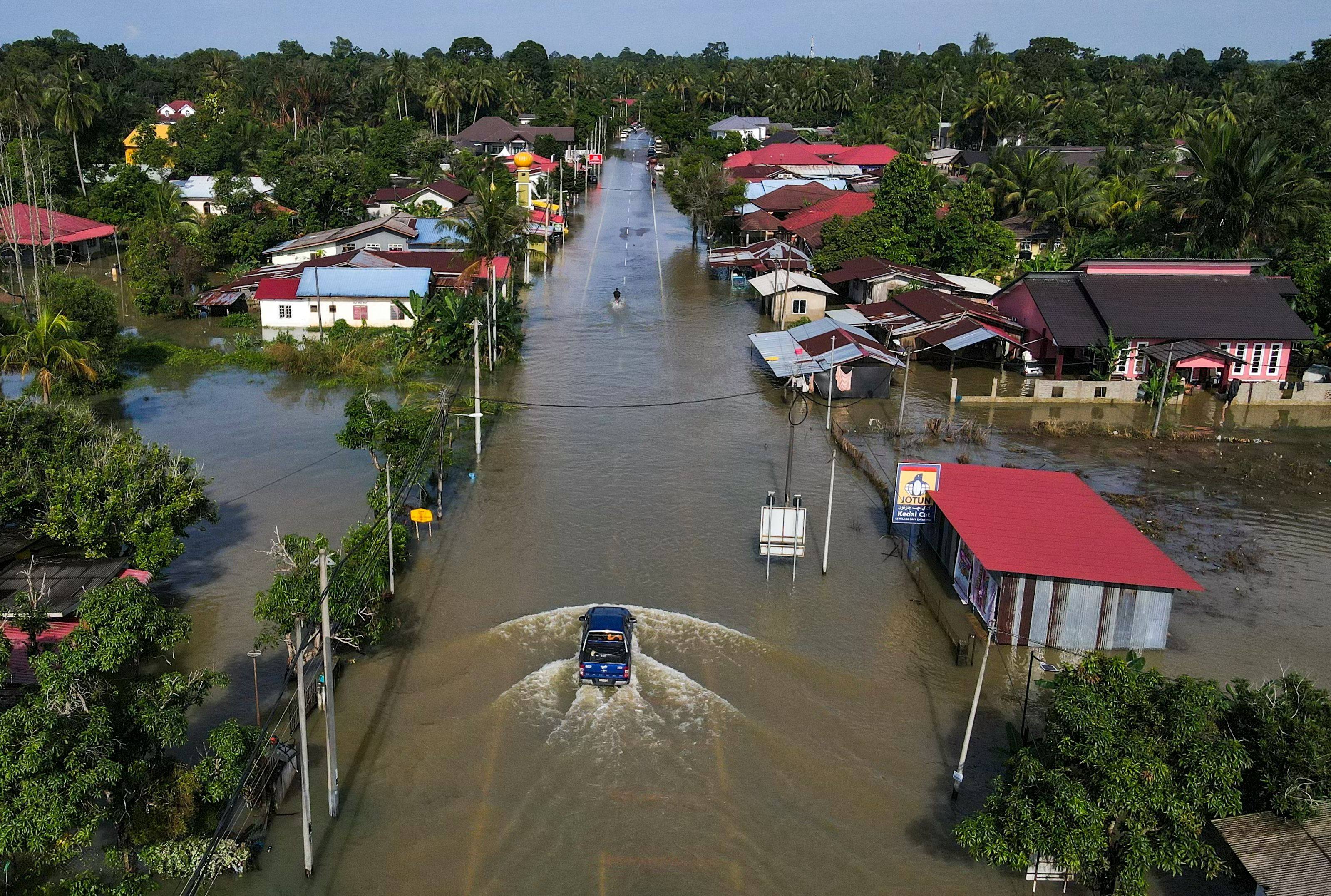 Vehicles traverse a flooded road in Malaysia’s Kelantan state on Monday after heavy rain. Photo: AFP