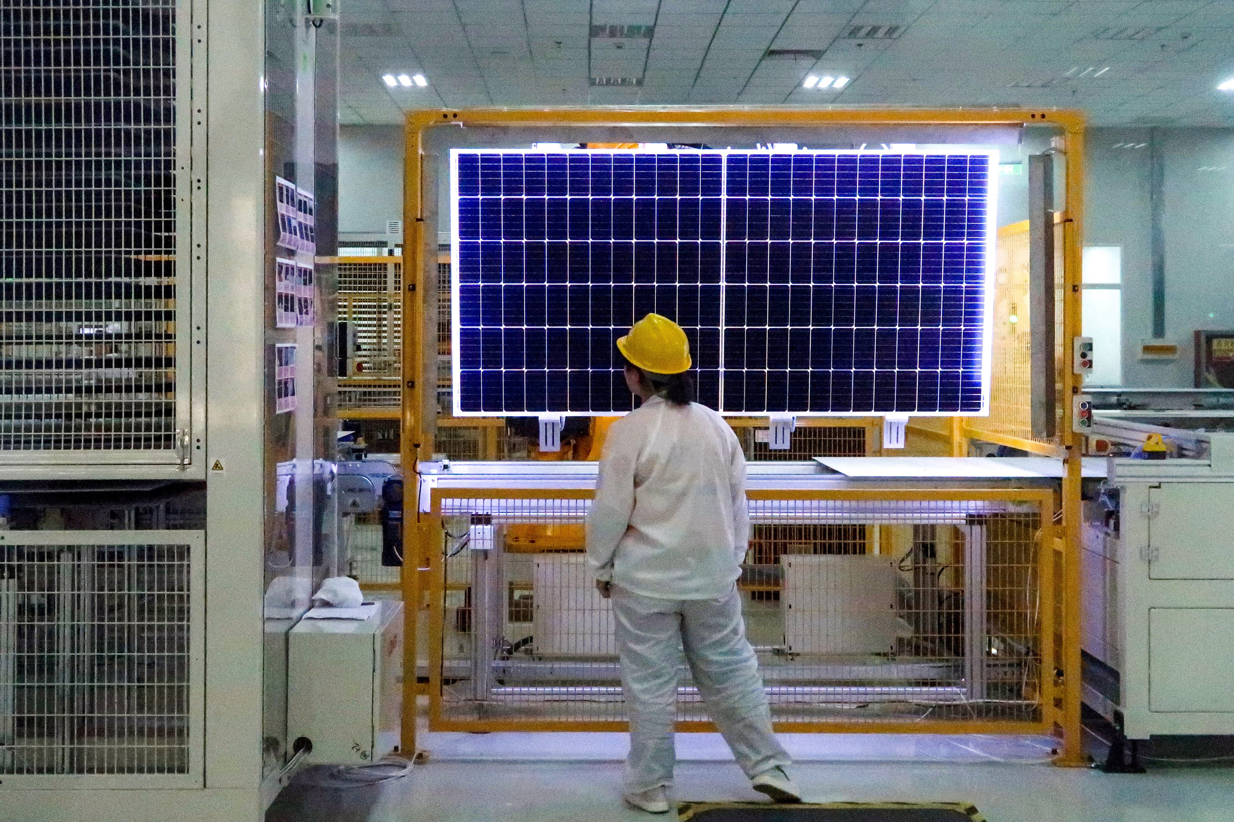 A worker conducts quality-check of a solar module. Photo: Reuters