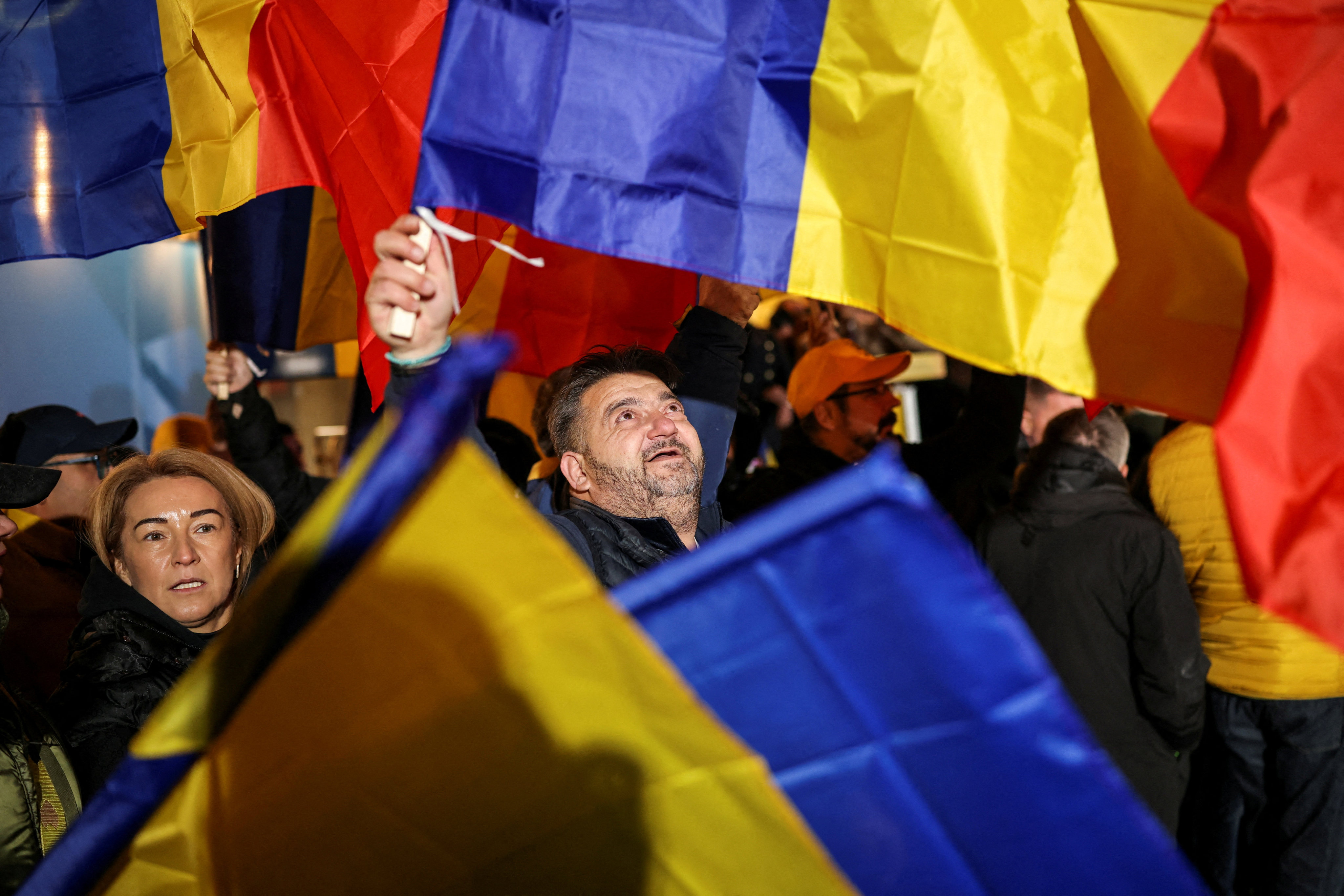 A supporter of the radical right Alliance for Uniting Romanians wave a Romanian flag, following the first exit polls, at the party’s campaign headquarters in Bucharest, Romania, December 1. Photo: Reuters