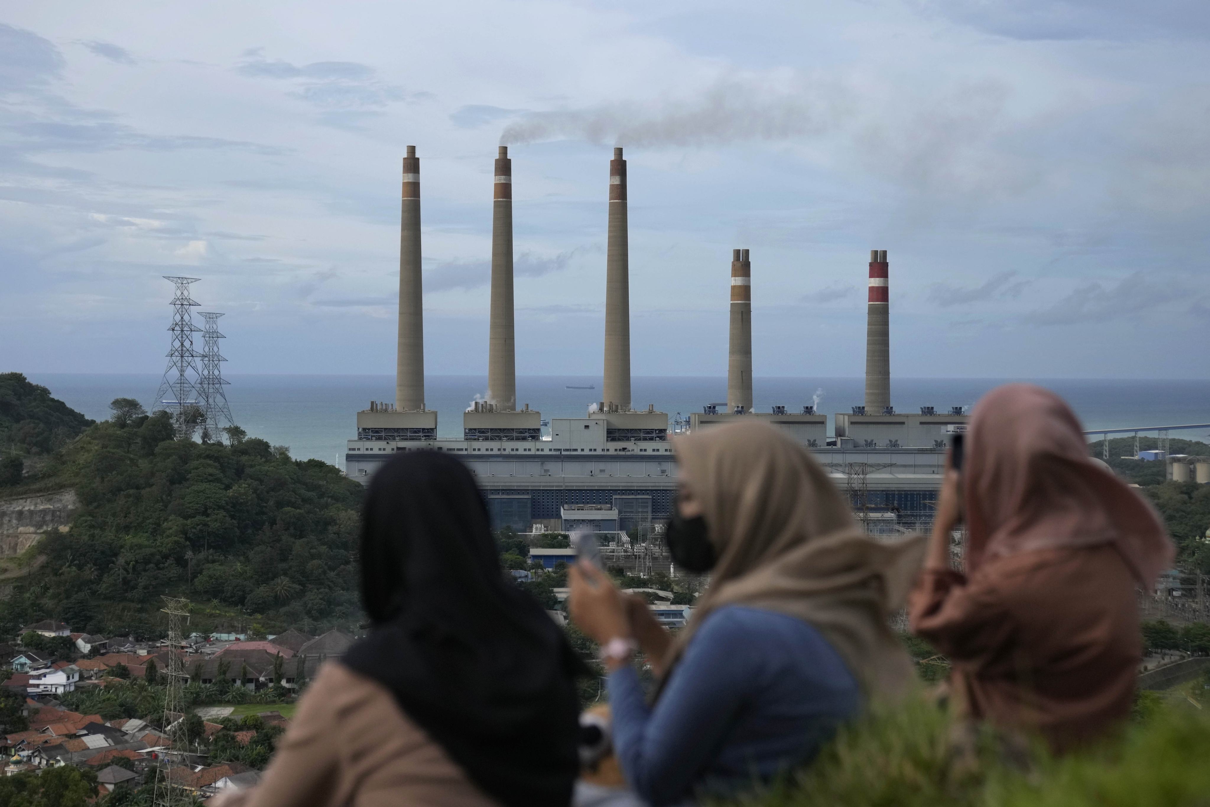 Women sit on a hill overlooking the Suralaya coal power plant in Cilegon, Indonesia, in 2023. Photo: AP