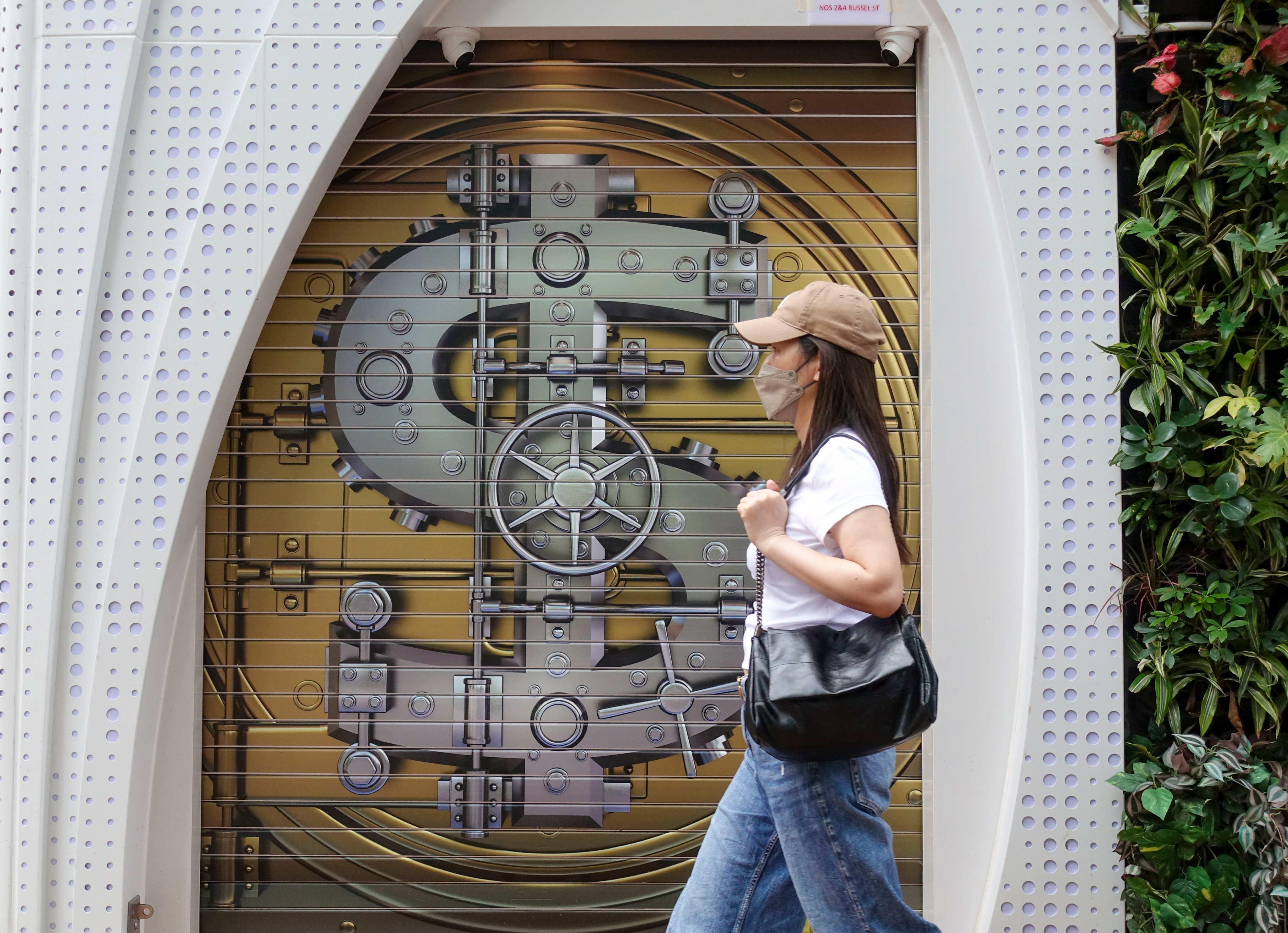 A woman walks past a currency-exchange shop in Causeway Bay with a bank vault painted on its gate, on May 5, 2024. Photo: Jelly Tse