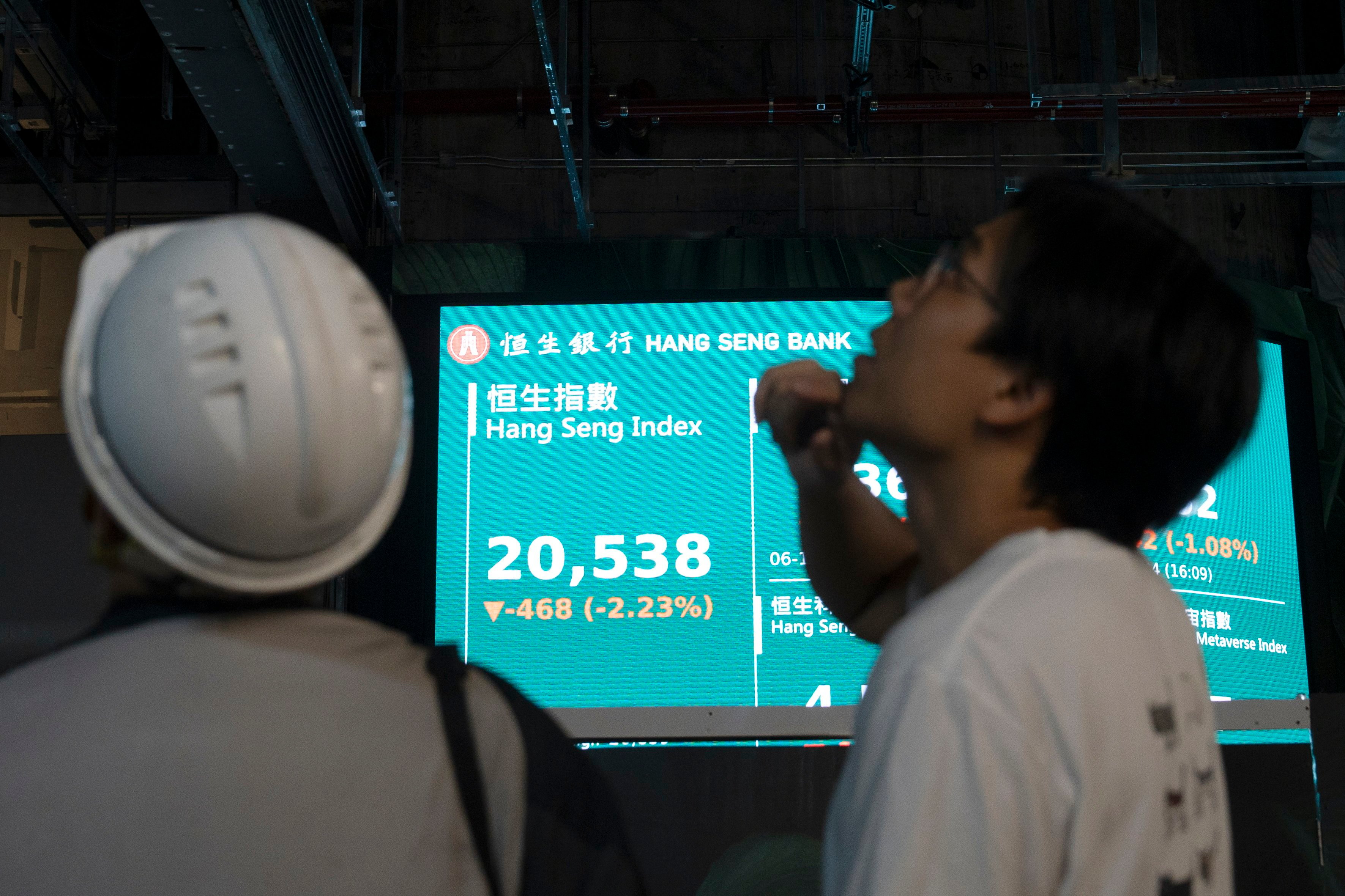 Workers look at stock screens while an electronic board shows the Hang Seng Index on November 6, 2024. Photo: EPA-EFE