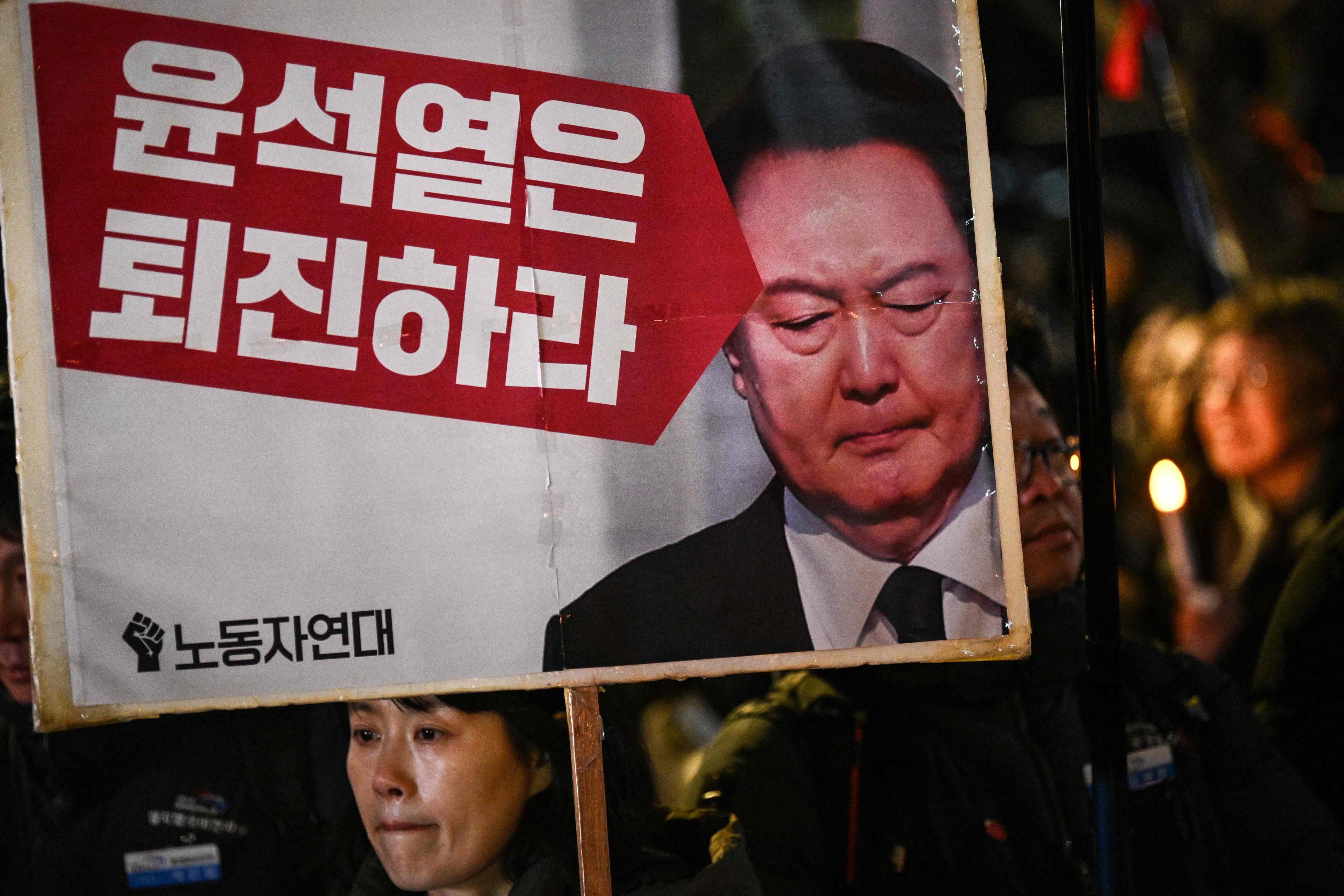 A woman holds a sign that reads “Yoon Suk Yeol should step down” during a vigil against South Korea President Yoon in Seoul on Wednesday. Photo: AFP