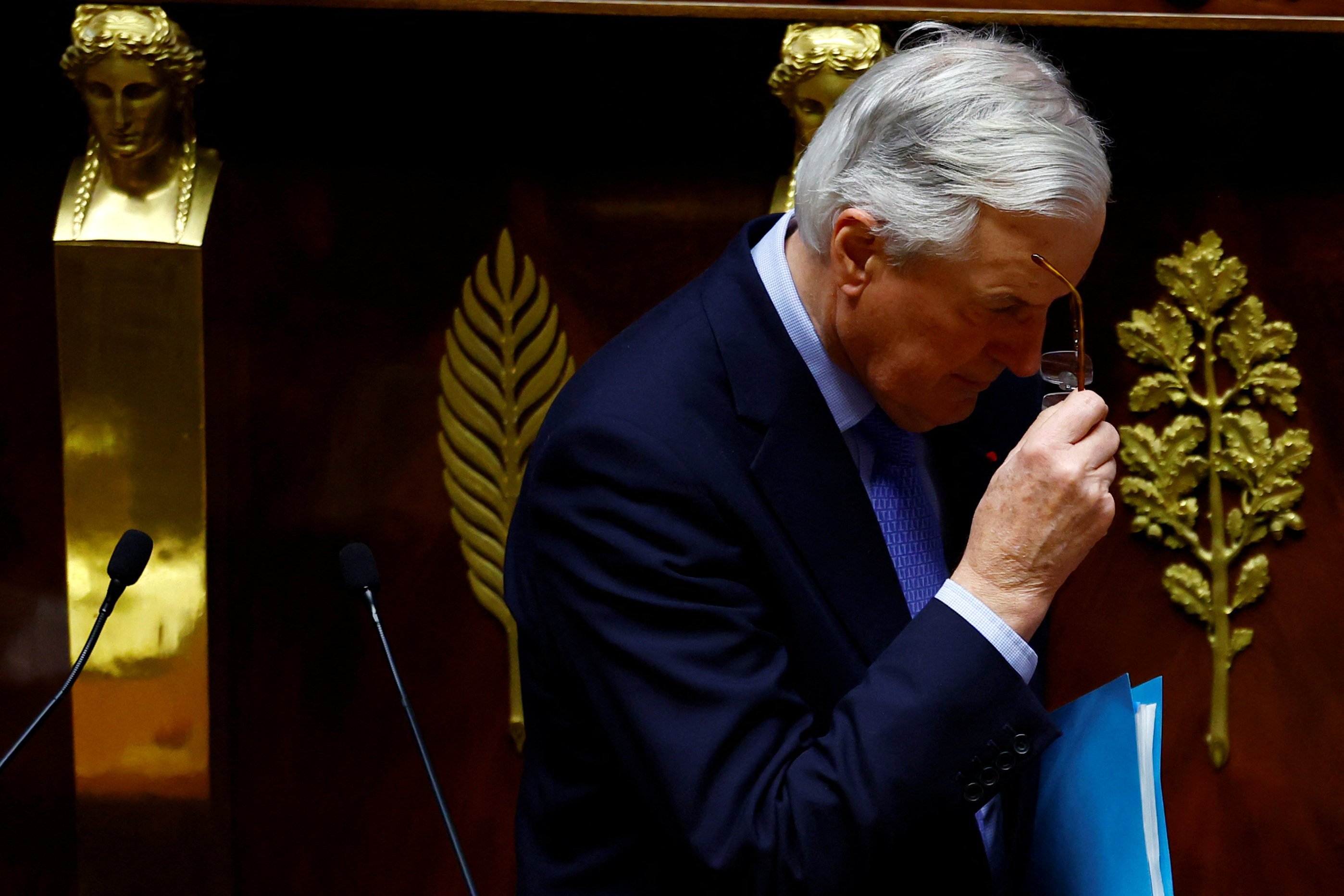 French Prime Minister Michel Barnier removes his glasses after giving a speech during a debate on two motions of no-confidence against the French government in Paris on Wednesday. Photo: Reuters