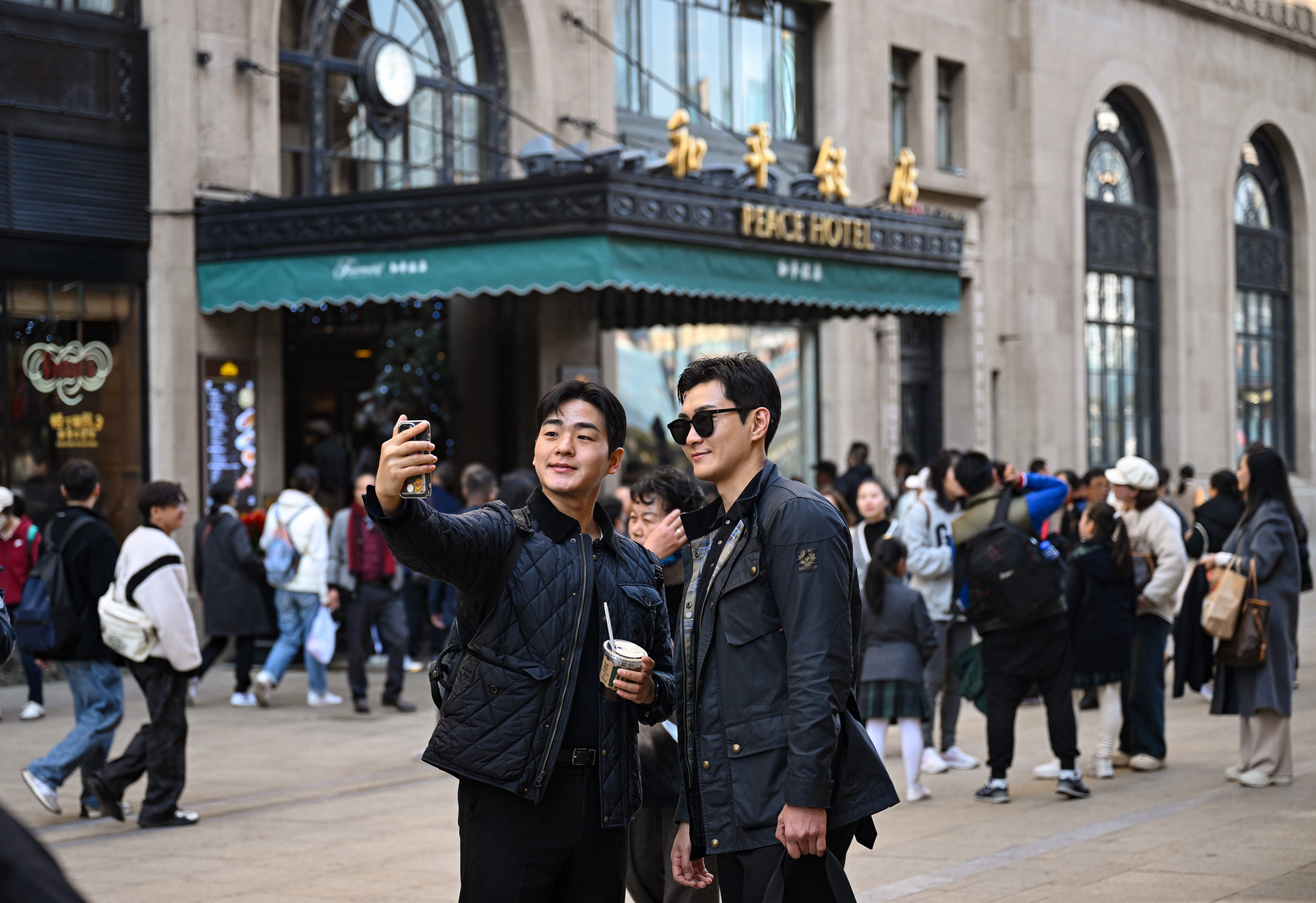 Tourists pose for selfies in front of the Peace Hotel in Shanghai. The number of foreign visitors flocking to China is starting to resemble pre-pandemic levels. Photo: Xinhua