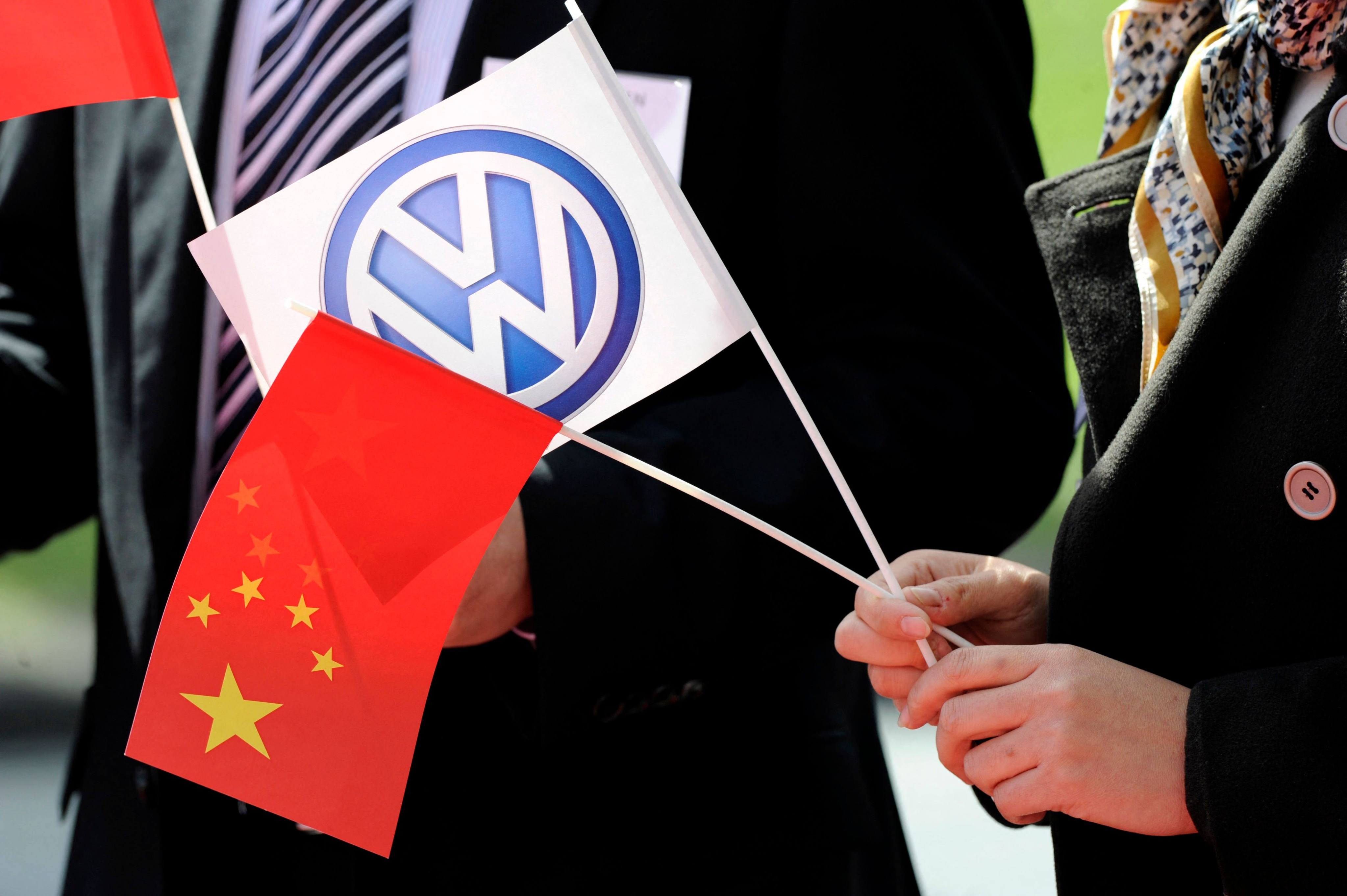 A person holds China’s national flag and a flag bearing the VW logo during a signing ceremony at the Volkswagen plant in Wolfsburg, Germany, in April 2012. Photo: AFP