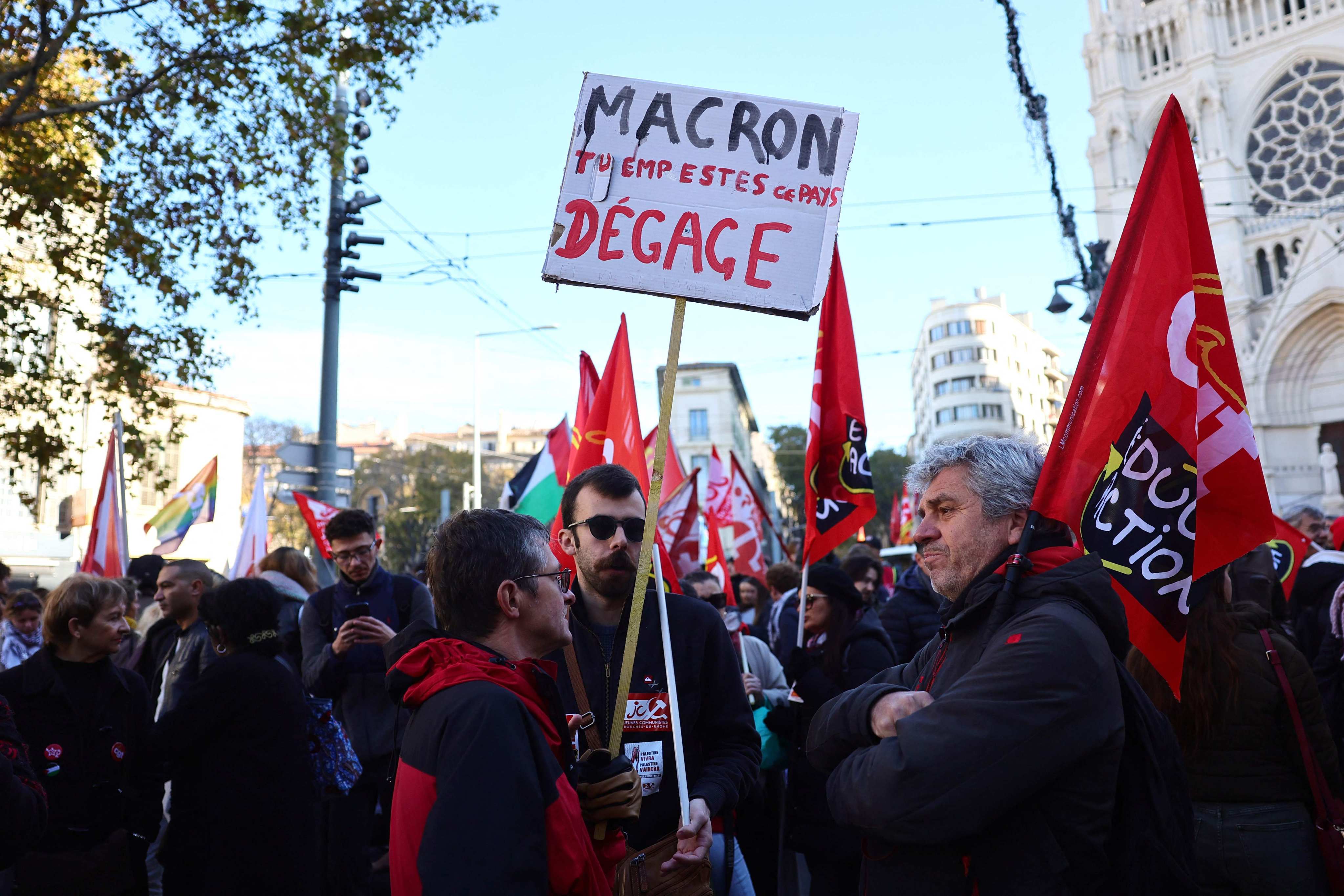 A protester holds a placard reading “Macron, you stink, get out” during a rally in Marseille. Photo: AFP