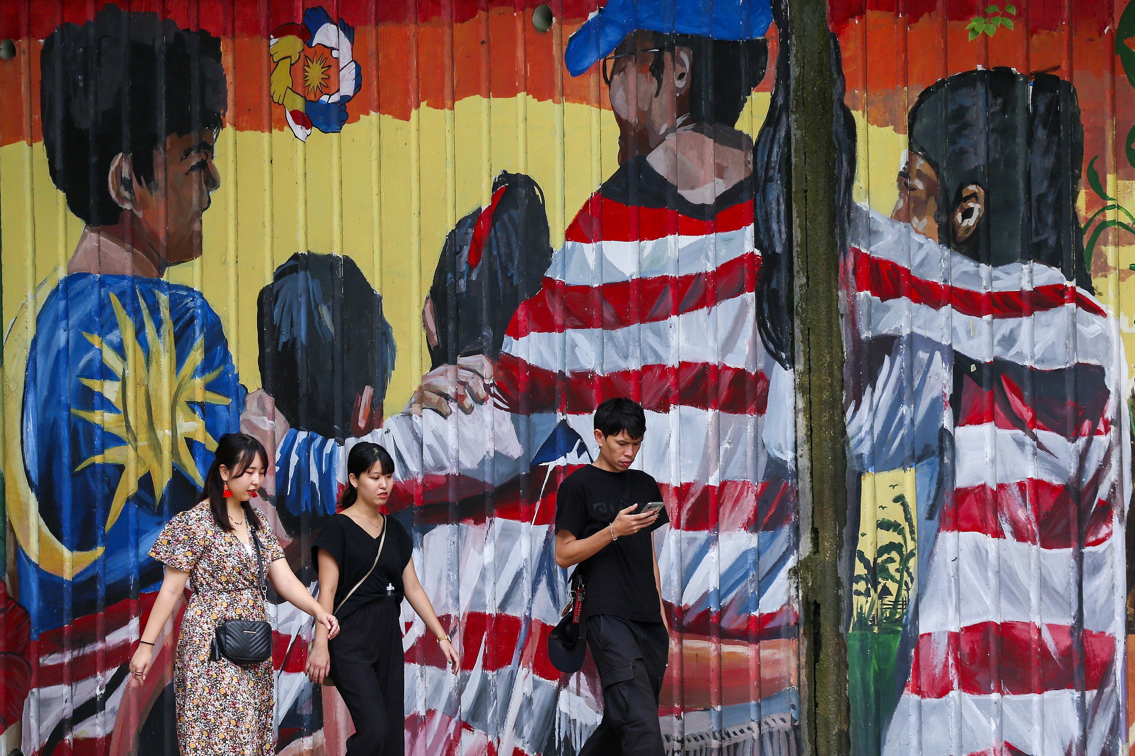 Tourists walk past a mural featuring the Malaysian national flag in Kuala Lumpur. Photo: EPA-EFE