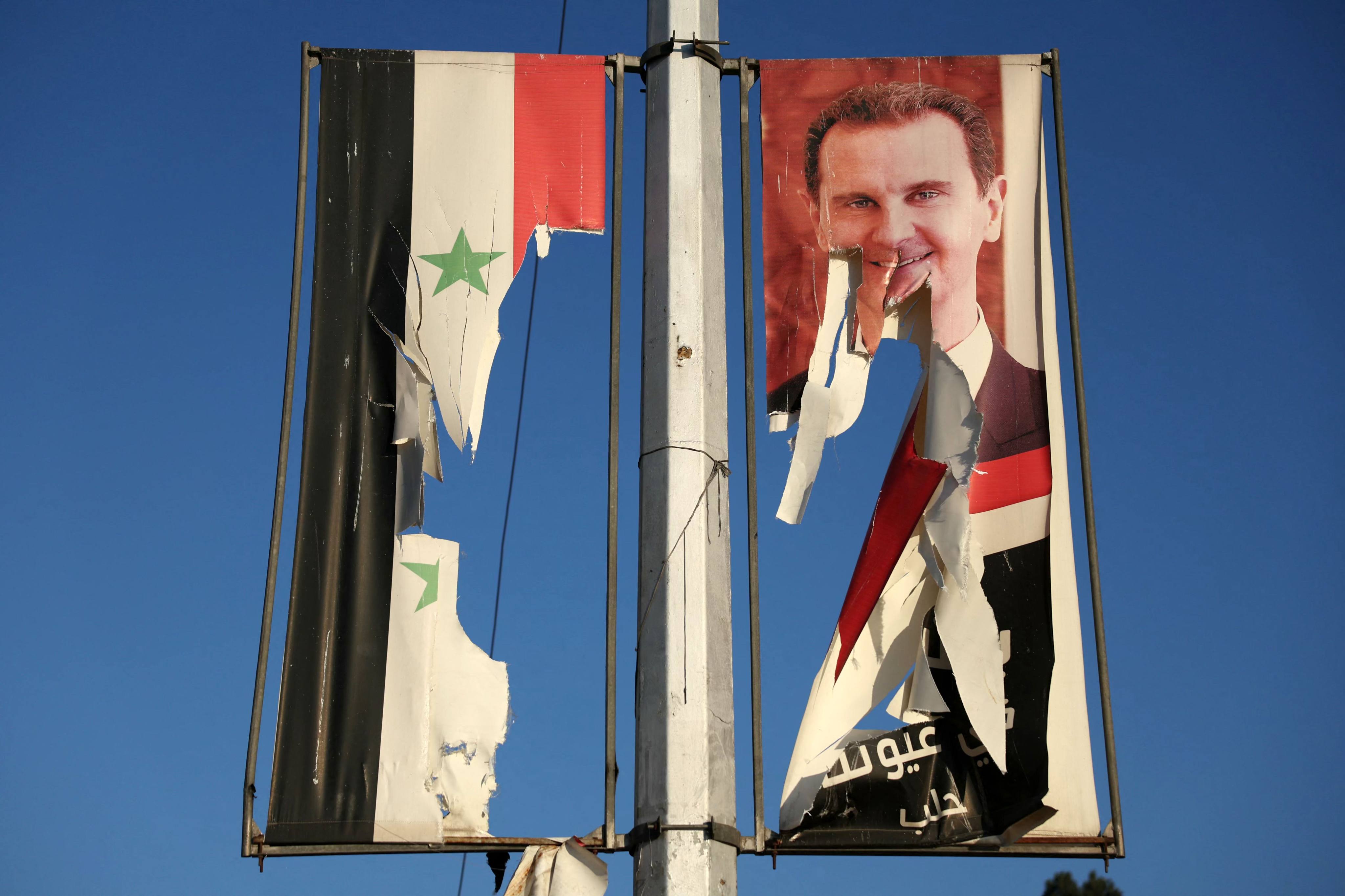 A billboard bearing a picture of Syria’s President Bashar al-Assad and a national flag that were torn by anti-government fighters in the northern city of Aleppo. Photo: AFP