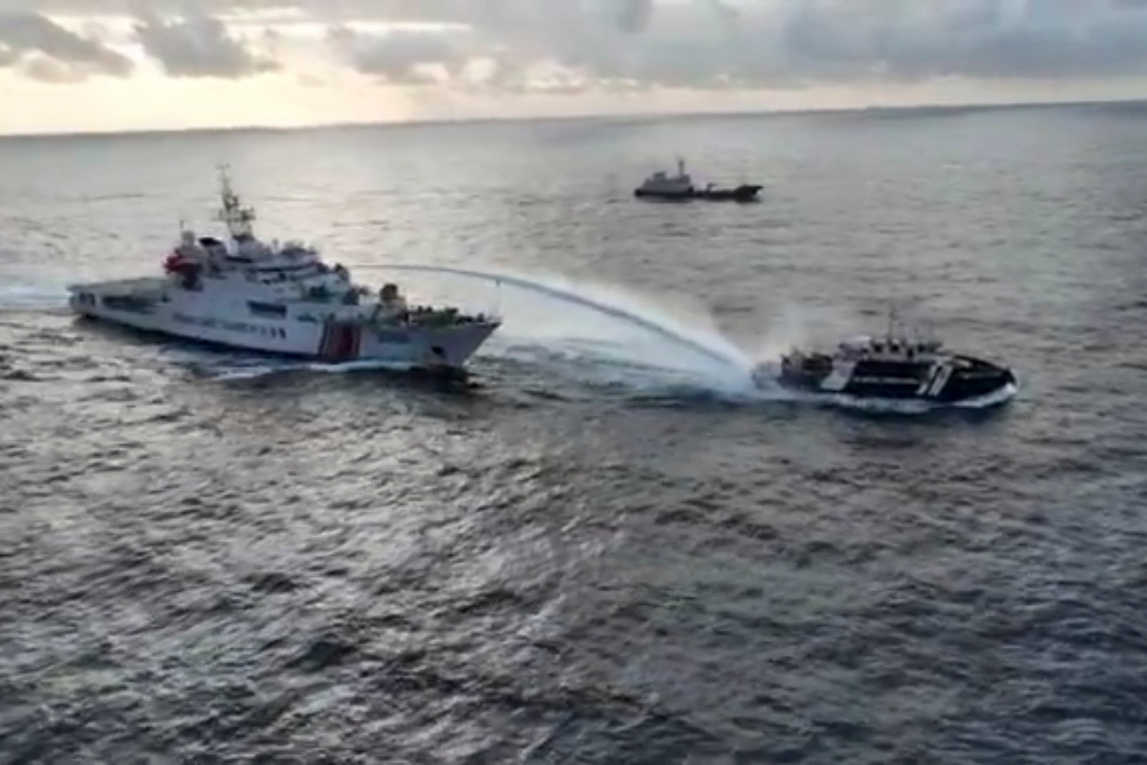 A Chinese coastguard vessel (left) fires a water cannon at a Philippine fishing vessel near a disputed shoal in the South China Sea on December 4. Photo: National Task Force for the West Philippine Sea/AP