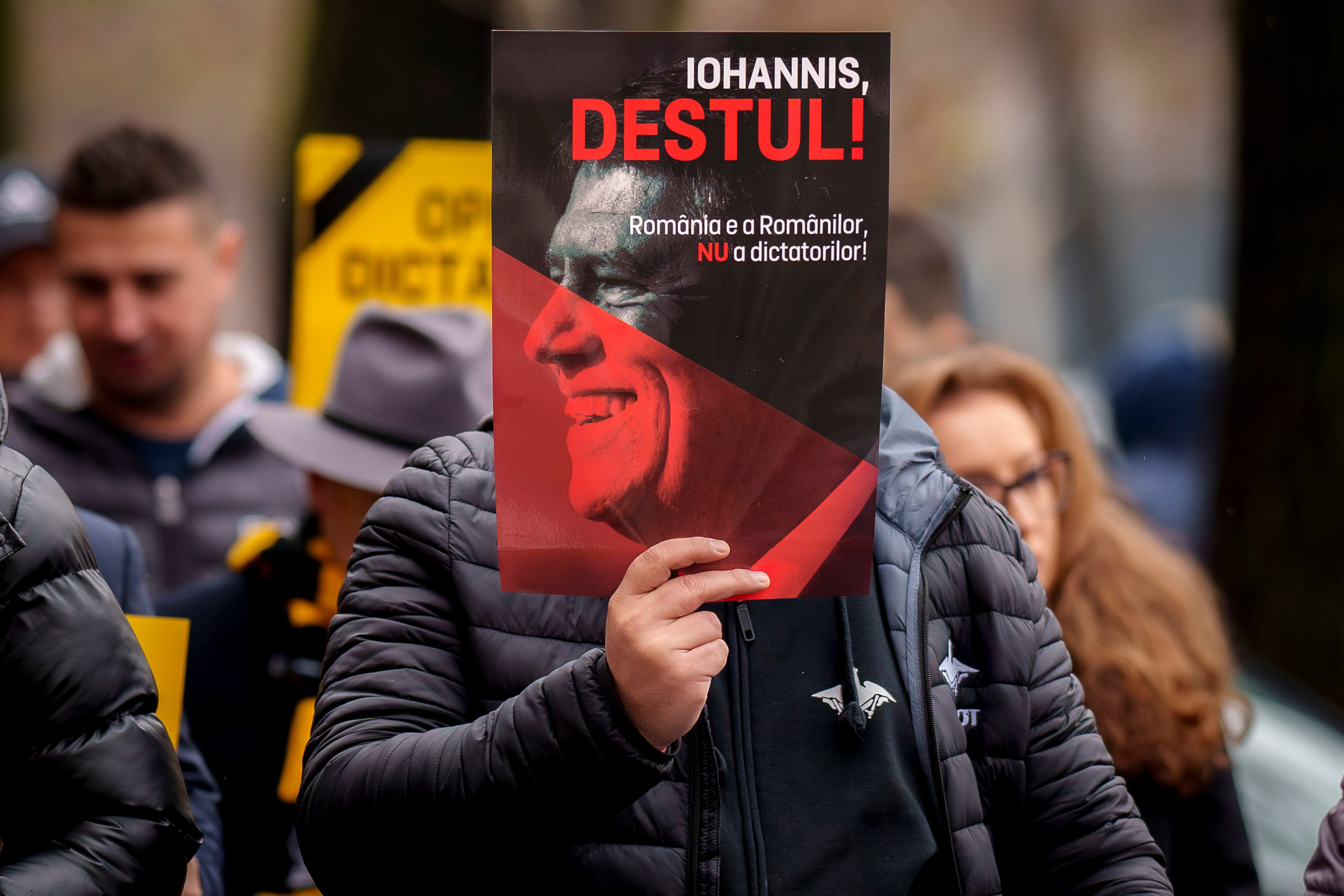 A supporter of the right wing Alliance for Unity of the Romanians (AUR) holding a poster of Romania’s President Klaus Iohannis that reads “Iohannis Enough - Romania belongs to Romanians, not to dictators” in Bucharest, Romania, on Sunday. Photo: AP