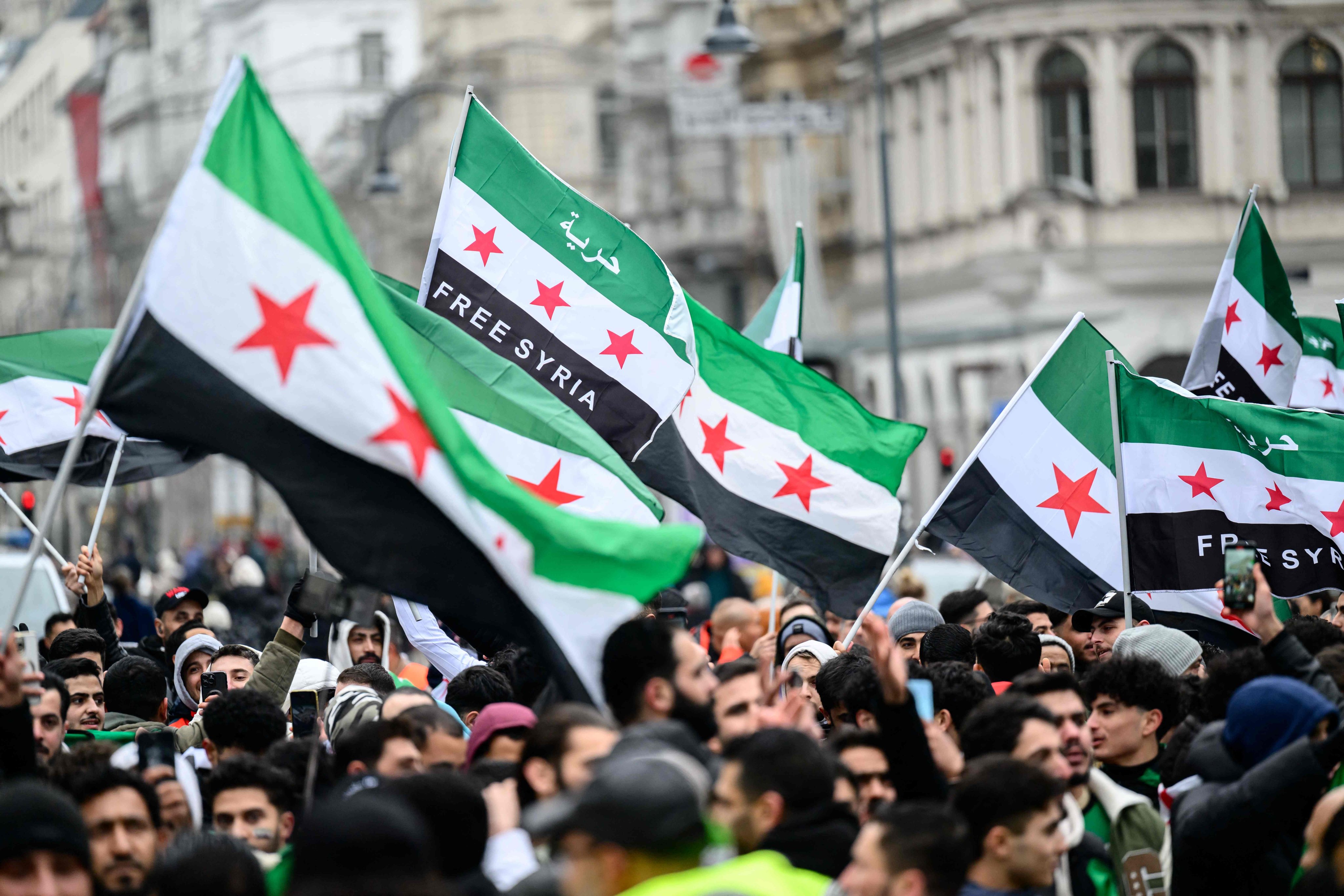 Members of the Syrian community wave Syrian flags on Sunday in Vienna, Austria. Photo: AFP